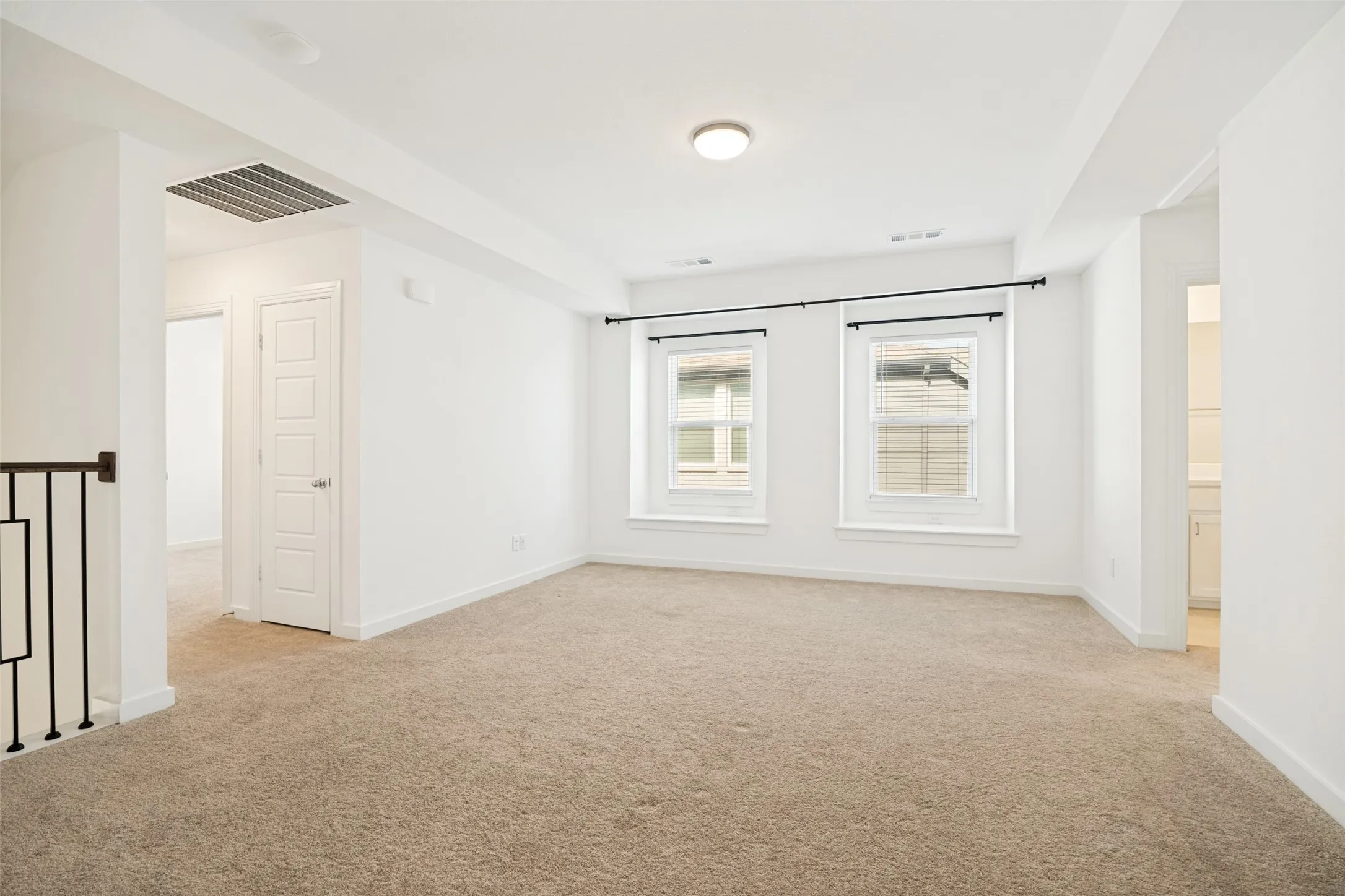 Carpeted upper-level living area with two windows featuring blinds and black curtain​​‌​​​​‌​​‌‌​‌‌​​​‌‌​‌​‌​‌​​​‌​​ rods