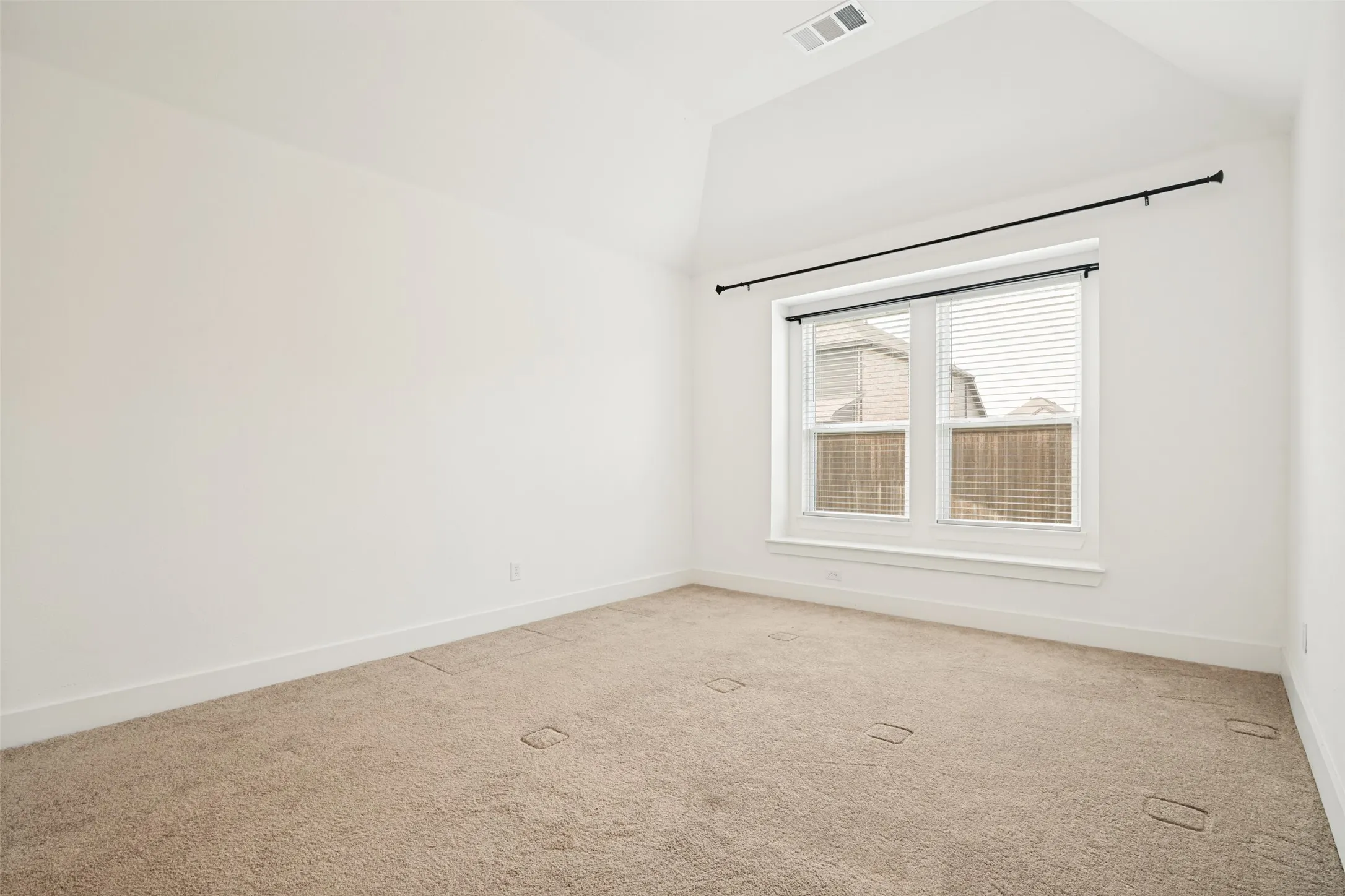 Bright room featuring a vaulted ceiling and an expansive window with blinds