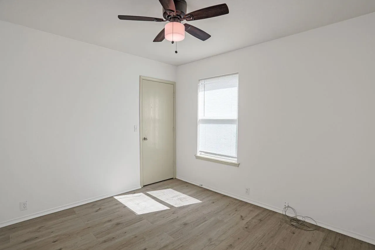 Bedroom featuring a ceiling fan with light fixture, wood-finish flooring, and white baseboards