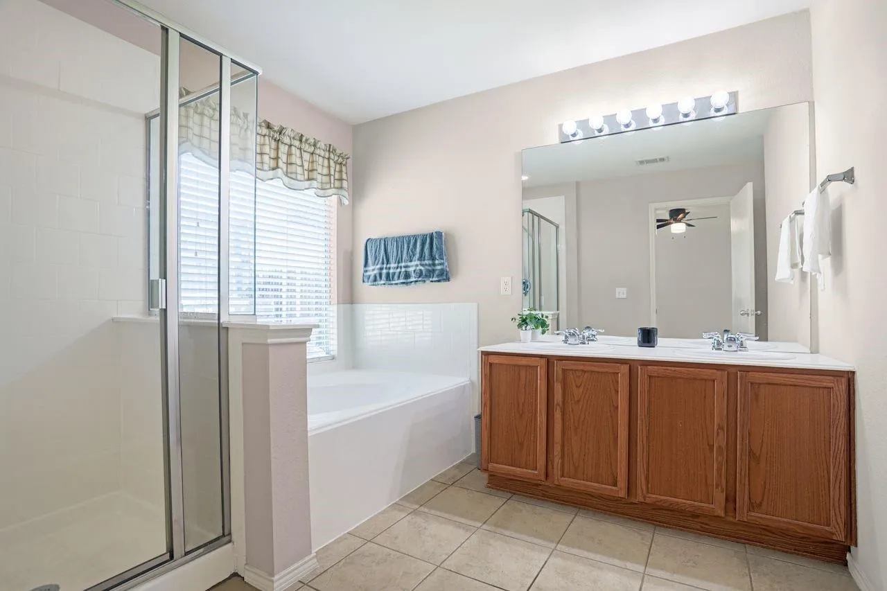 Bathroom featuring a double vanity with wood-finish cabinetry, a large mirror, and a five-light fixture