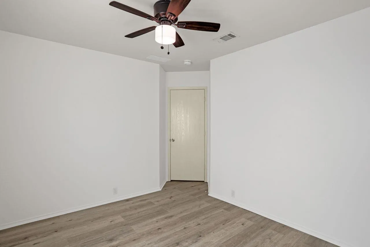 Interior room featuring light-toned wood-finish flooring and white baseboards