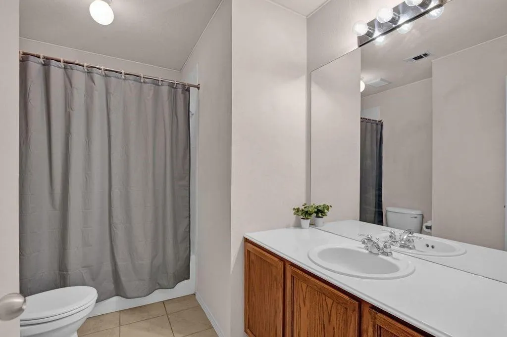 Bathroom featuring a dual-sink vanity with a white countertop and wood-finish cabinetry