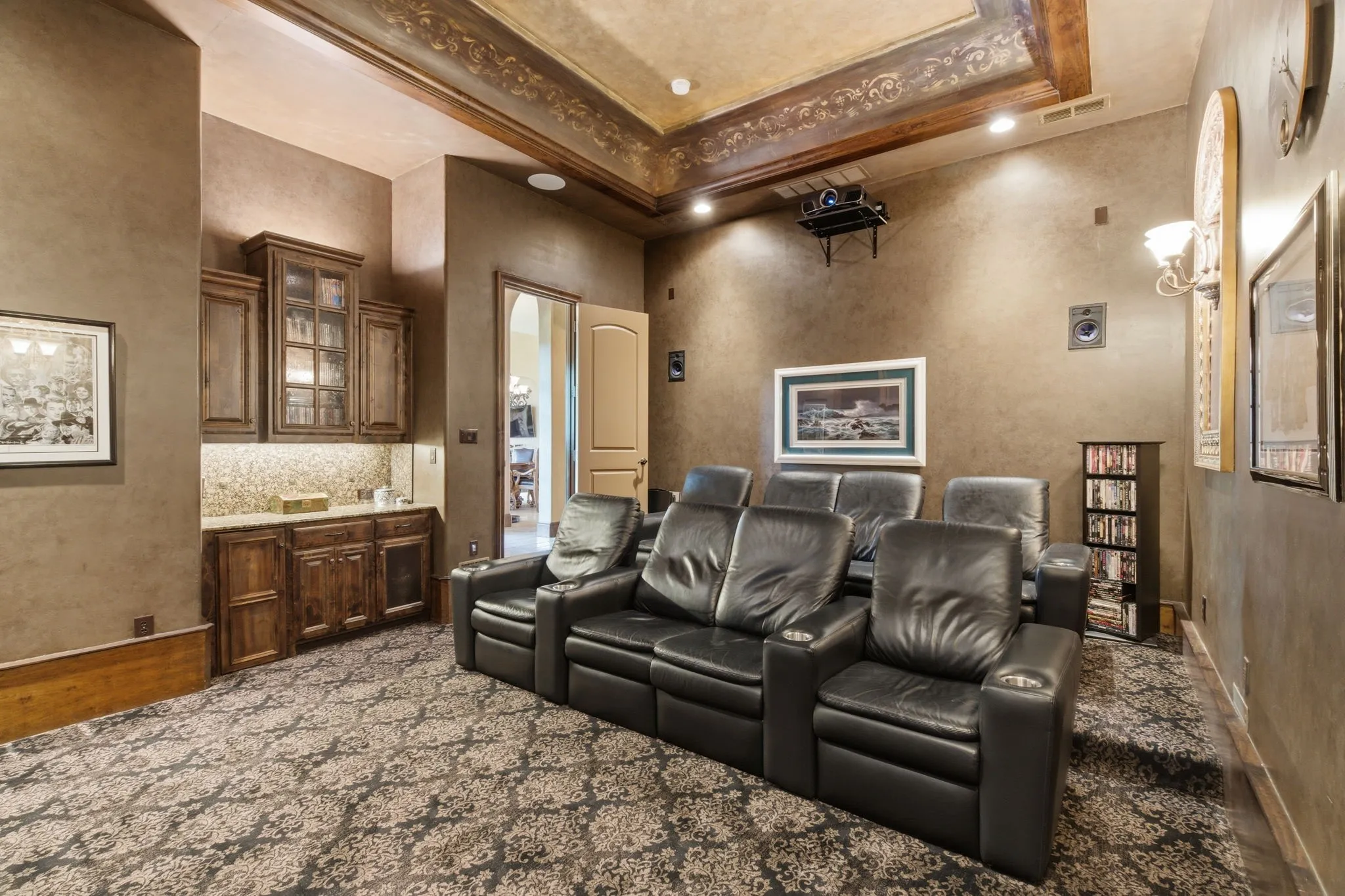 Dedicated media room featuring patterned wall-to-wall carpeting and a dry bar