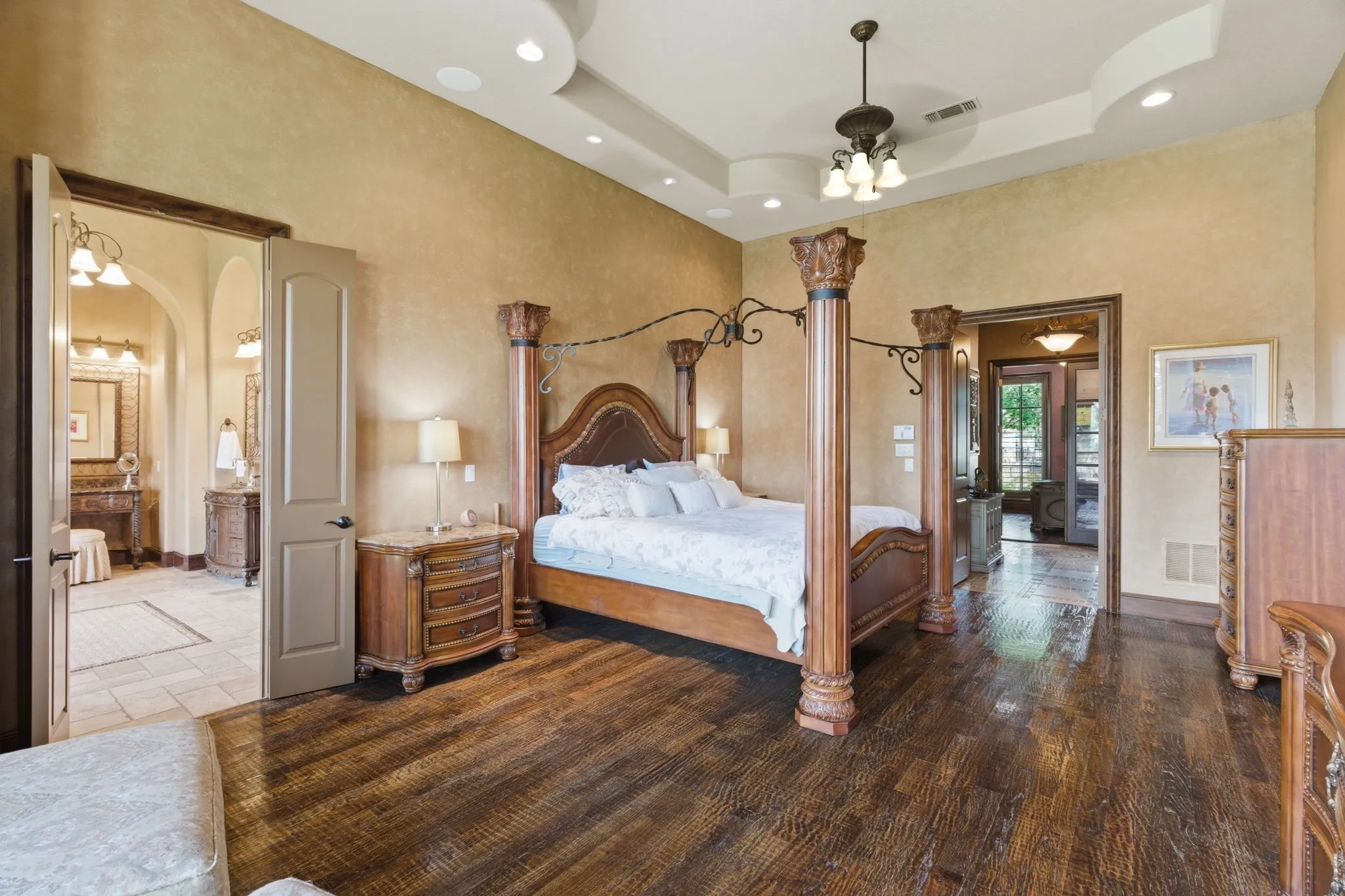High ceilings featuring a tray design with recessed lighting, dark wood-finish flooring, and a broad arched doorway