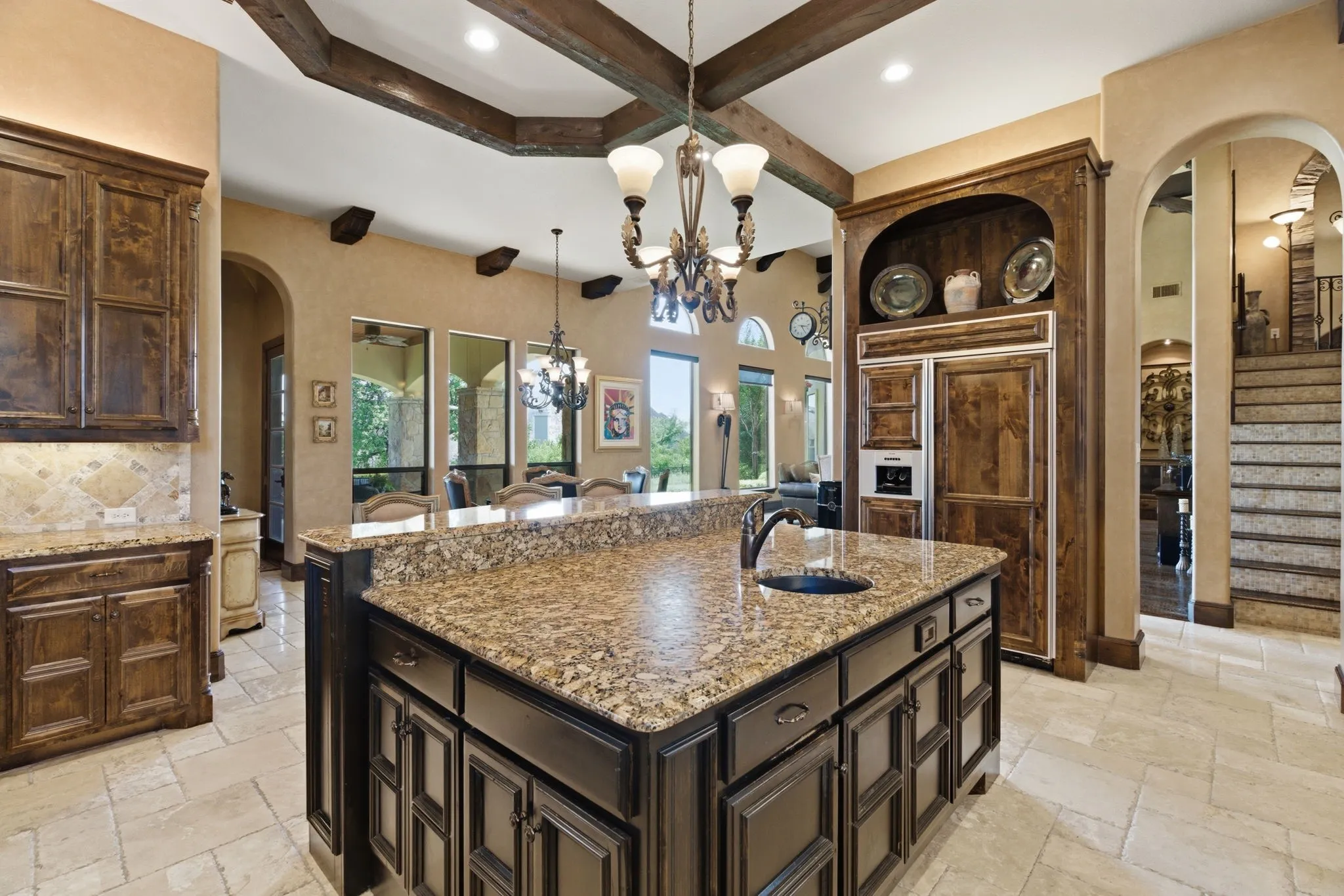 Kitchen island with an undermount sink and a dark faucet, surrounded by dark wood cabinetry and granite countertops
