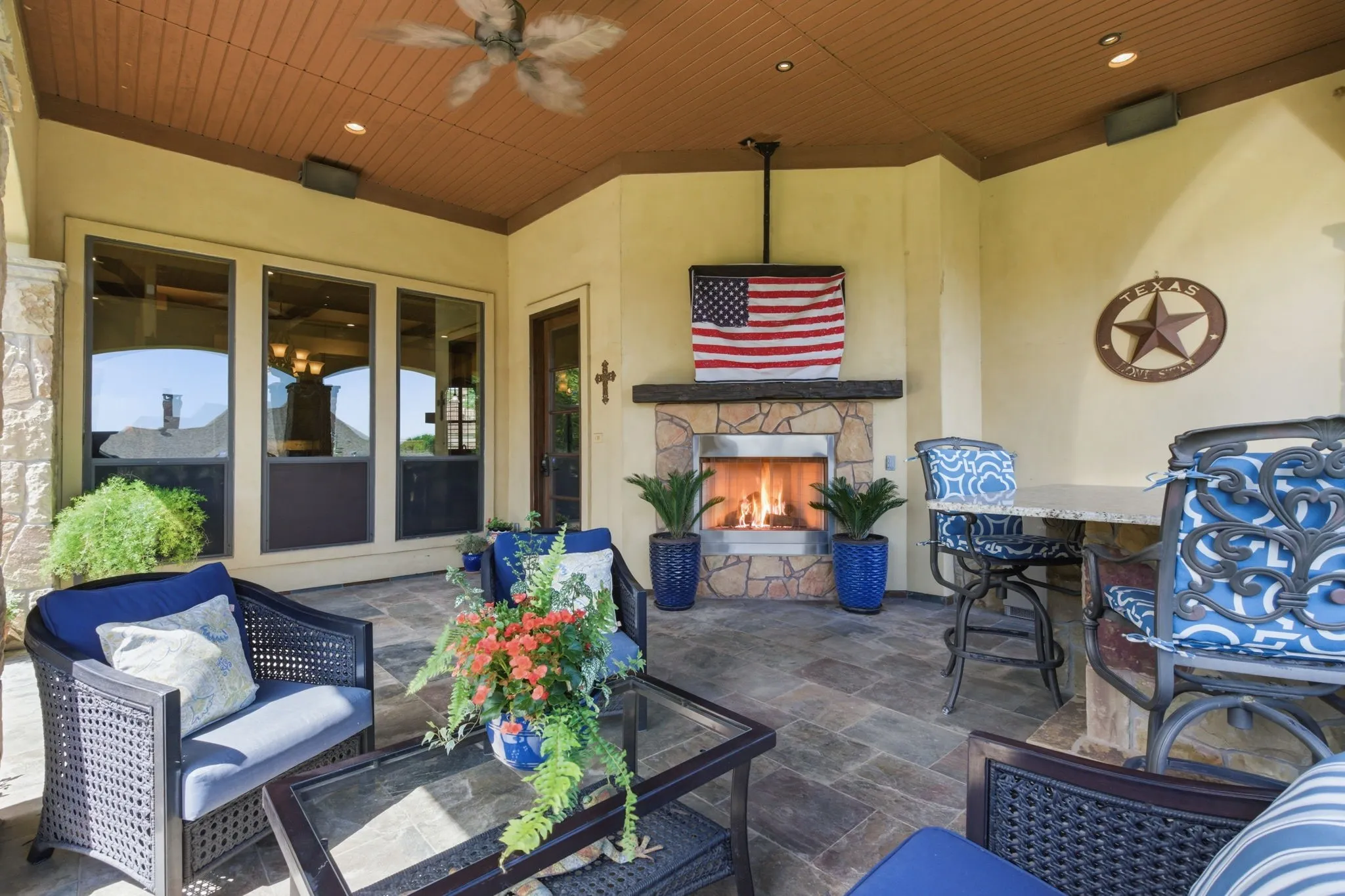 Covered patio with a stone-clad fireplace and mantle, recessed lighting, and a ceiling fan