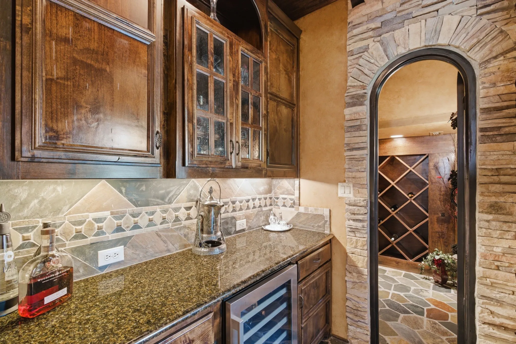 Butlers pantry featuring rich wood cabinetry, granite countertops, and a built-in beverage cooler