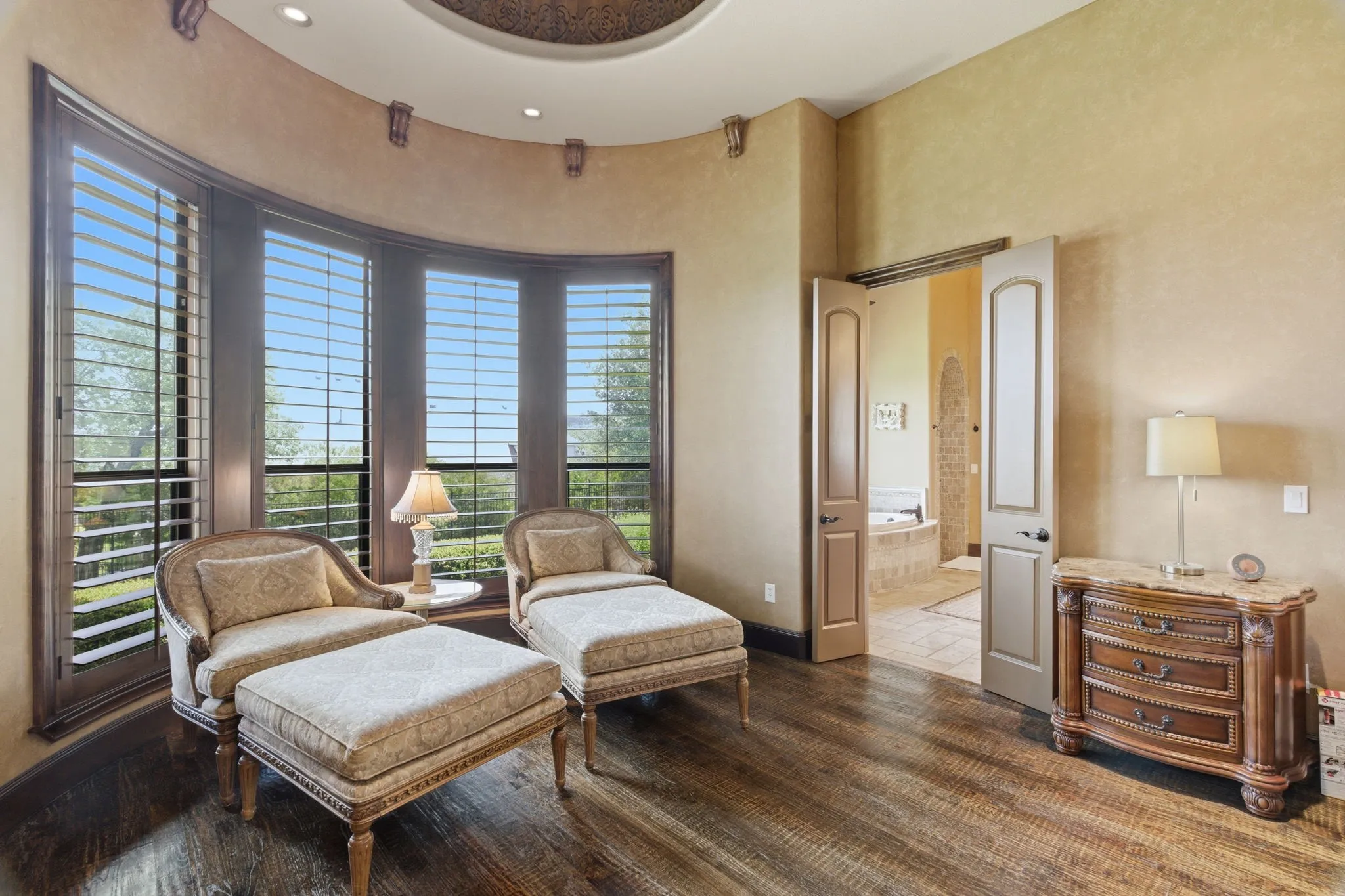 Curved bay windows featuring plantation shutters and dark wood-finish flooring