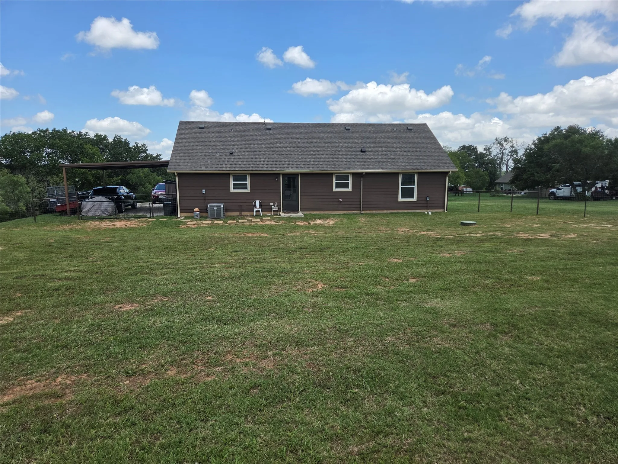 View of the back of house from large fenced in backyard