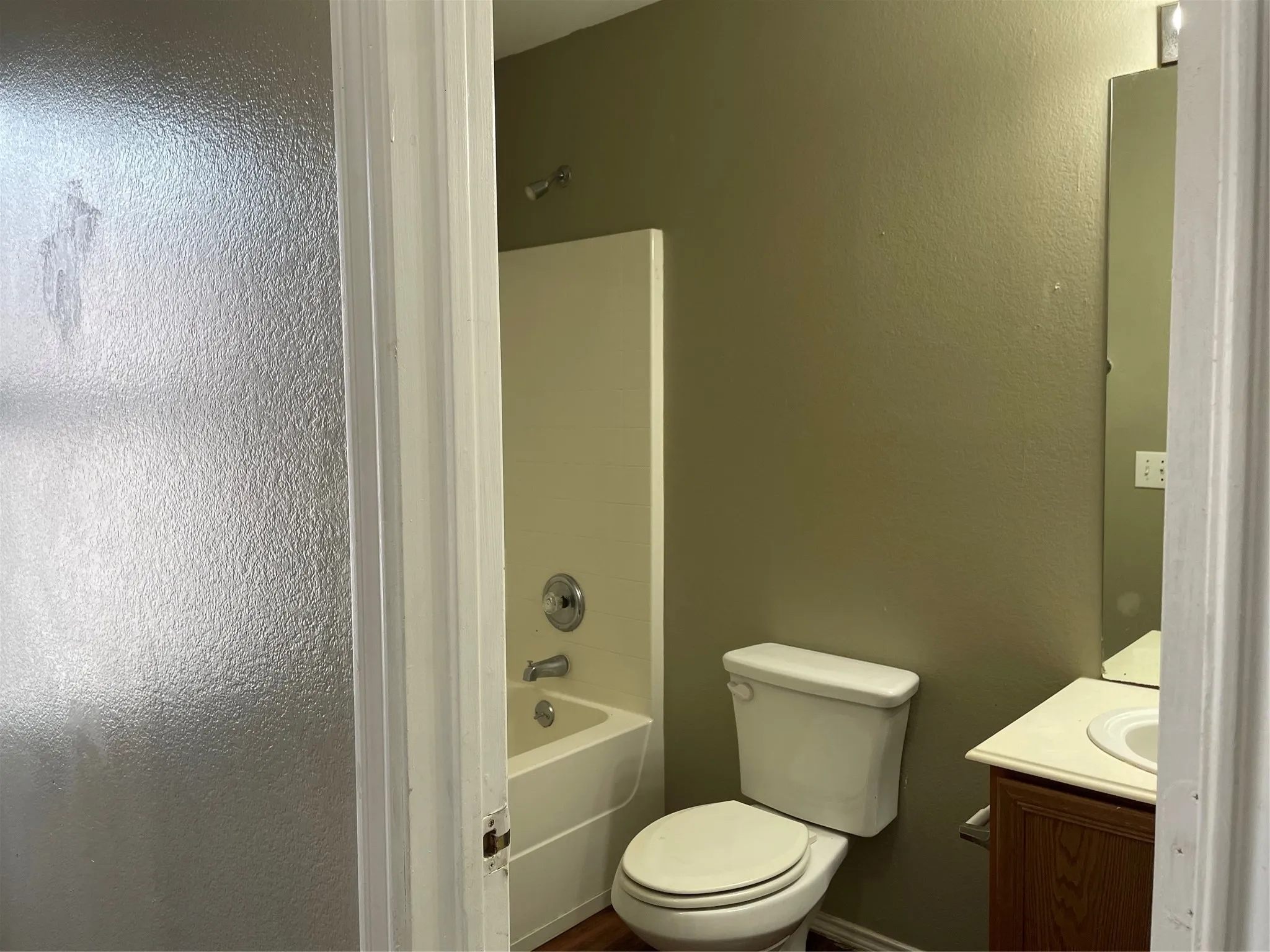 Bathroom featuring a built-in tub with shower, single vanity with a laminate countertop, and a wall-mounted mirror