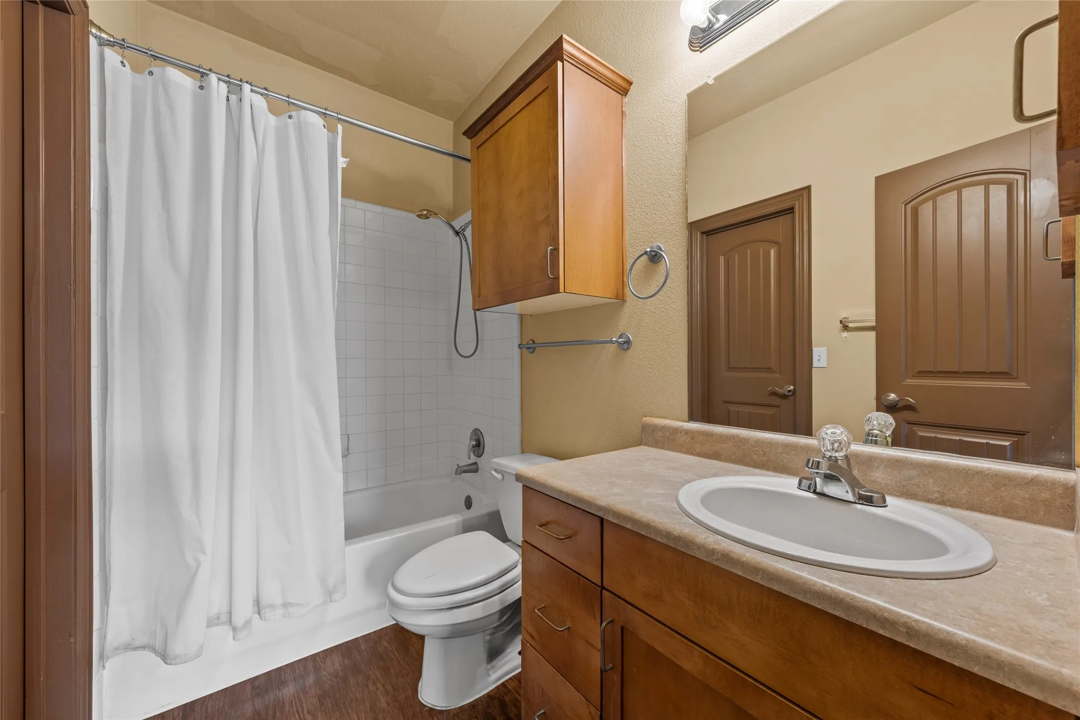 Bathroom featuring a wood-finish vanity with an integrated sink and laminate countertop