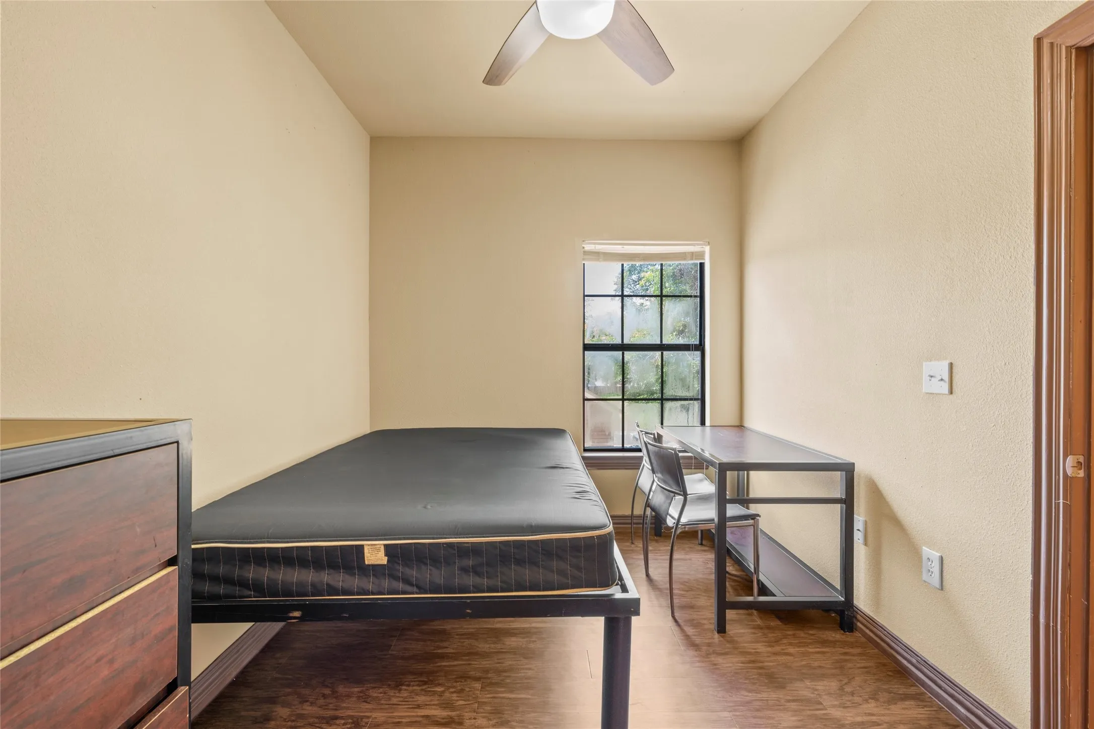 Room featuring wood-finish flooring, a window with exterior views, and a ceiling fan