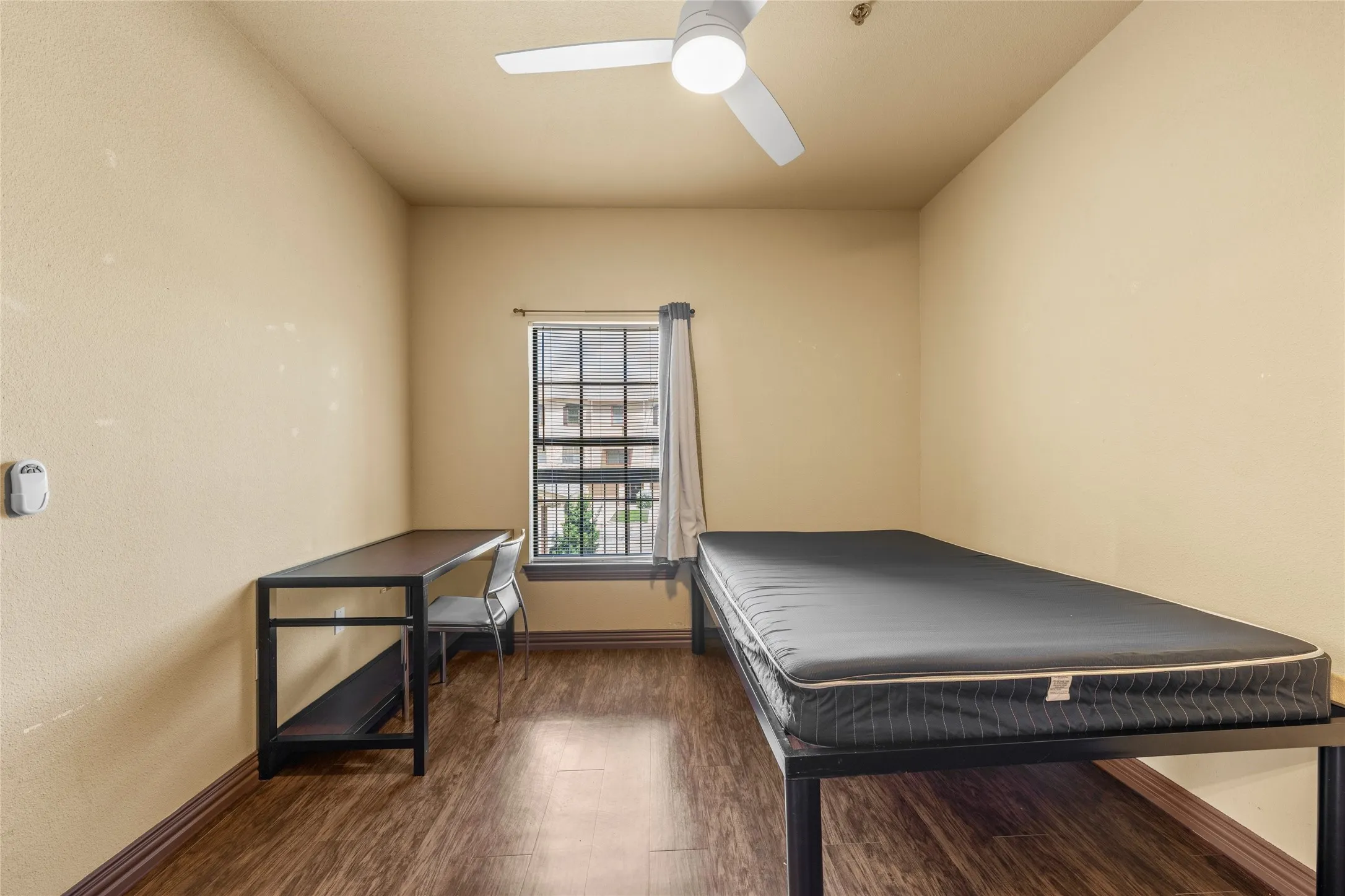 Bedroom featuring wood-finish flooring, a ceiling fan with integrated lighting, and a window with exterior views