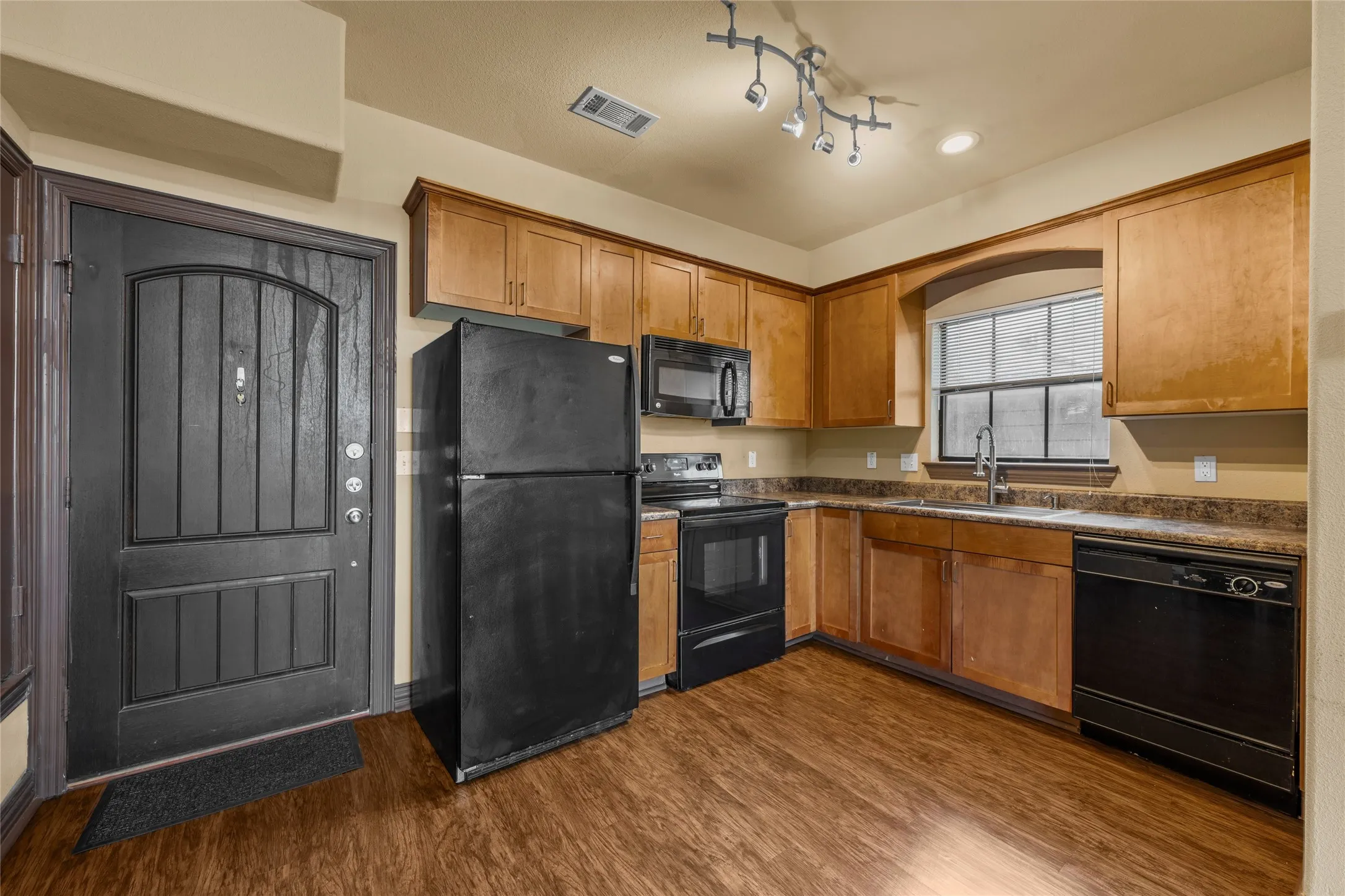 Kitchen area featuring wood-finish flooring, light wood cabinetry, and solid surface countertops