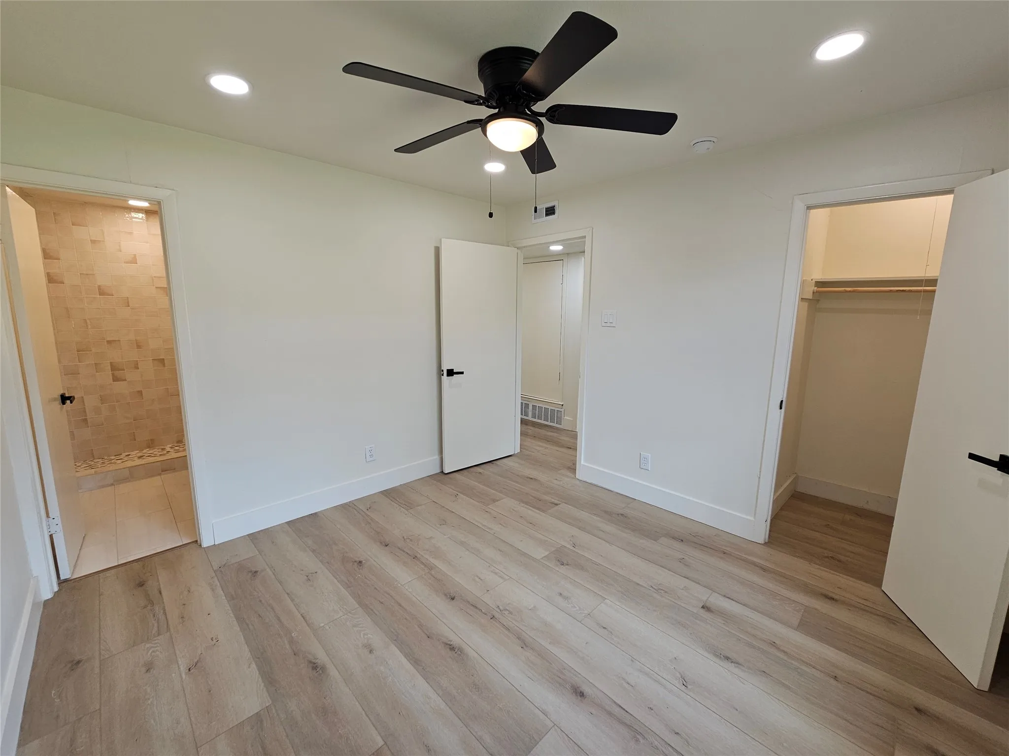 Spacious room featuring wood-finish flooring, a ceiling fan with light fixture, and recessed lighting