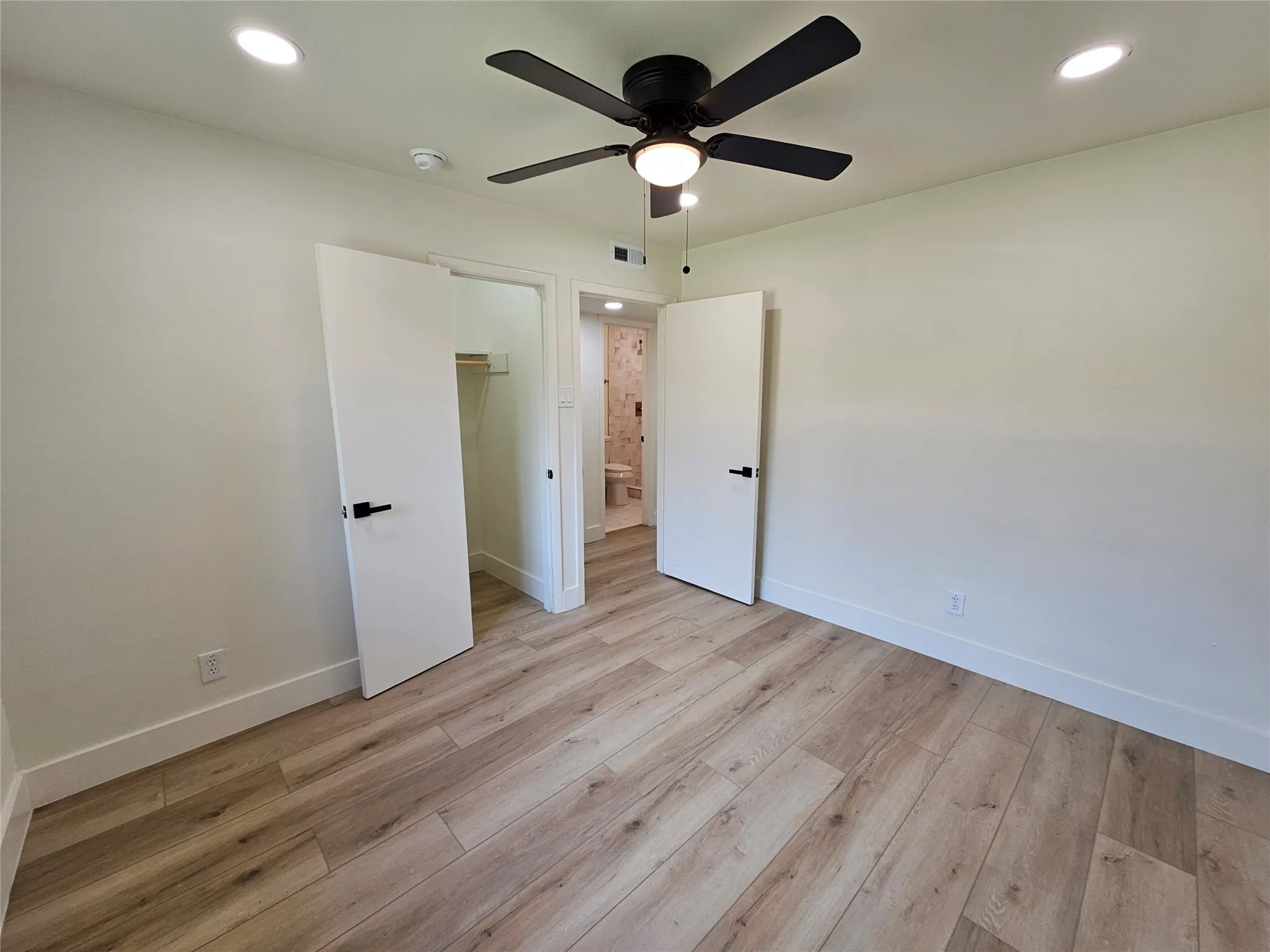 Bright interior space featuring light wood-finish flooring, recessed lighting, and a ceiling fan with integrated light