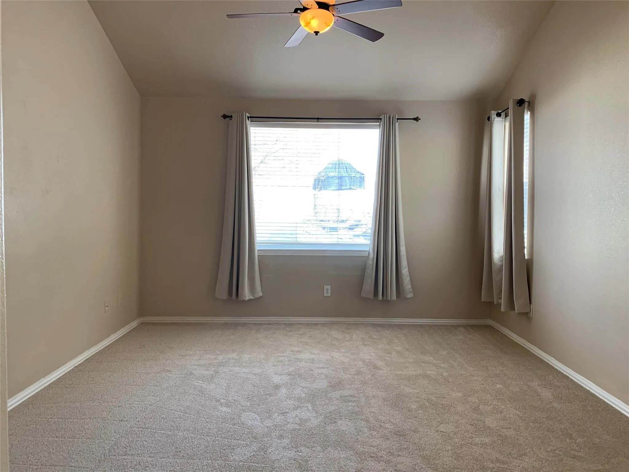 Carpeted room featuring a vaulted ceiling and a ceiling fan with light fixture