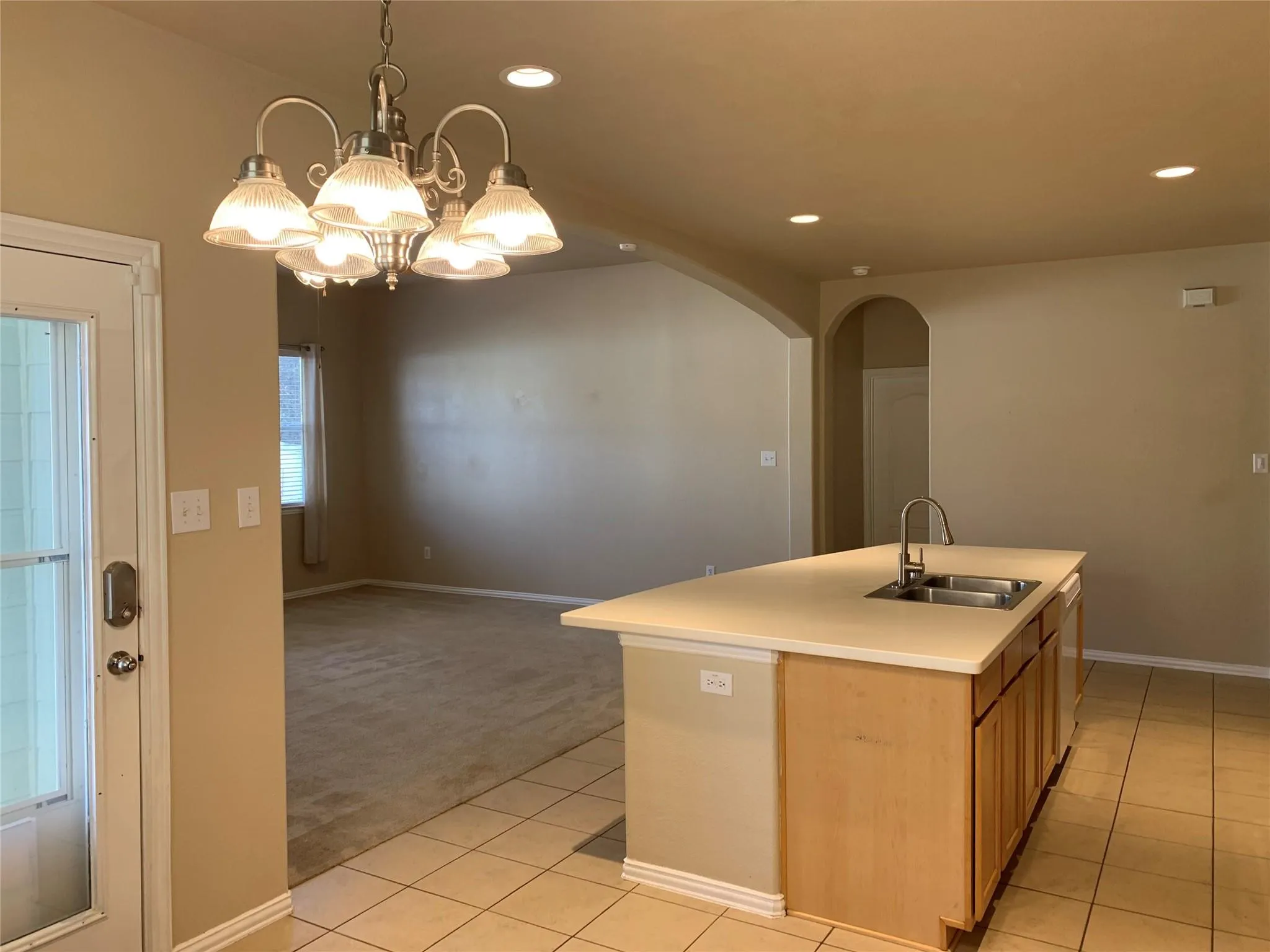 Kitchen island featuring light-toned cabinetry, a double basin sink with a gooseneck faucet, and a light countertop