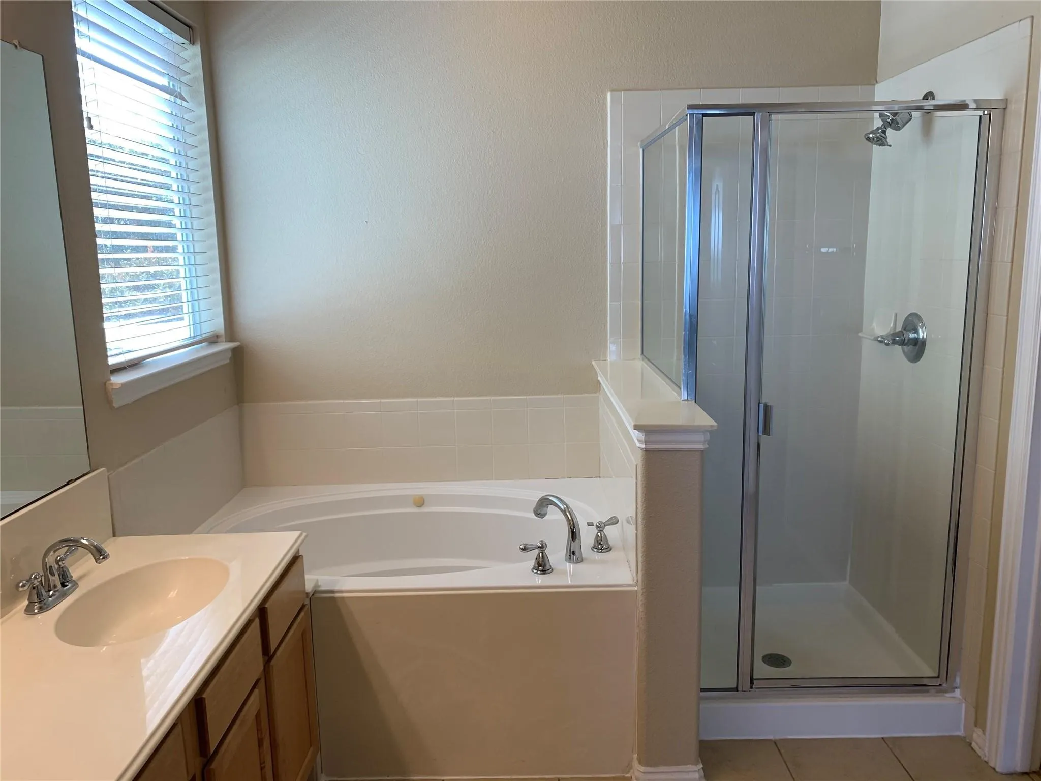 Bathroom featuring a corner soaking tub, separate glass-enclosed shower, single vanity with integrated sink, and wood-finish​​‌​​​​‌​​‌‌​‌‌​​​‌‌​‌​‌​‌​​​‌​​ cabinetry