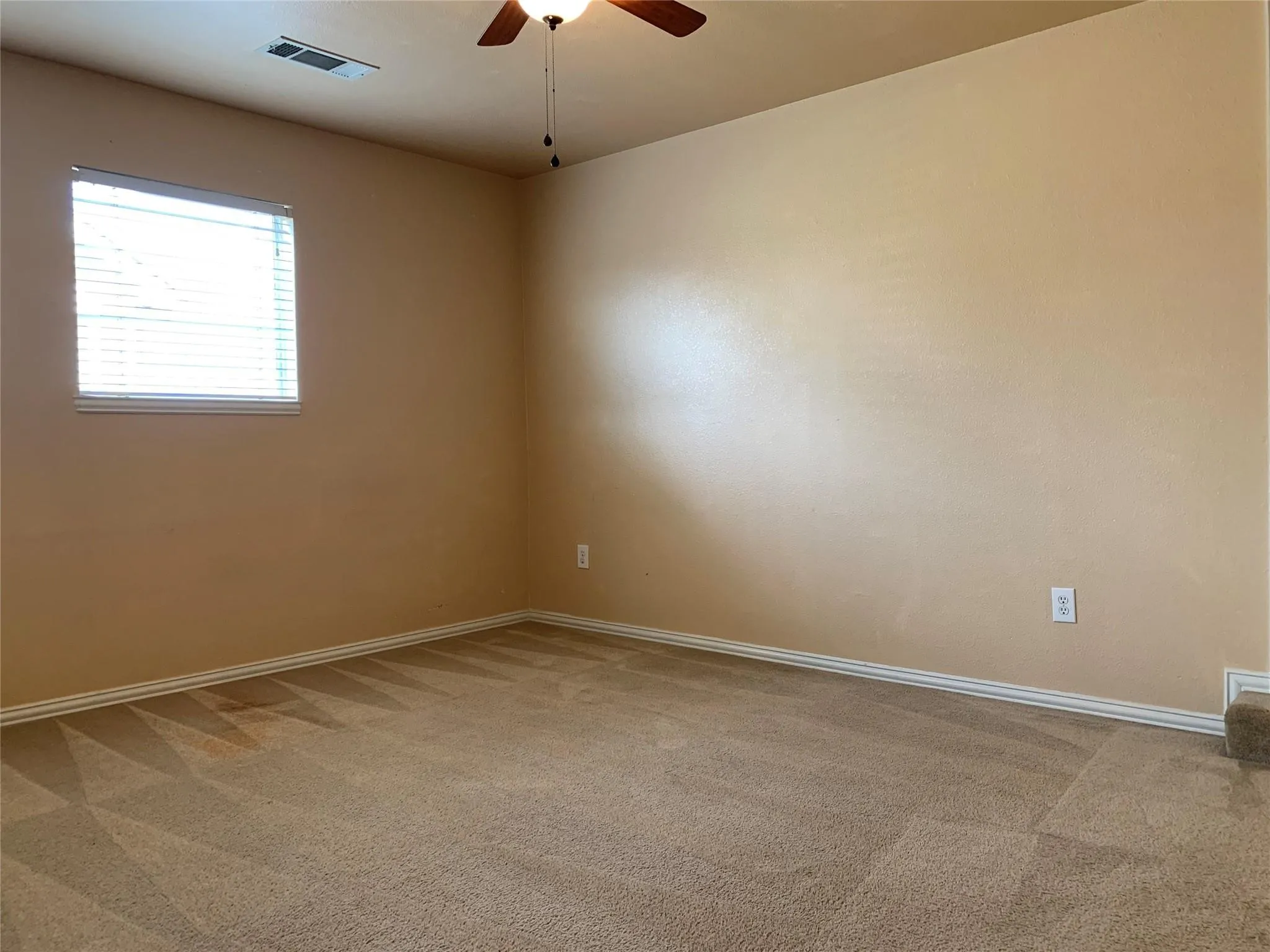Carpeted room with a ceiling fan, a window with blinds, and neutral-toned walls