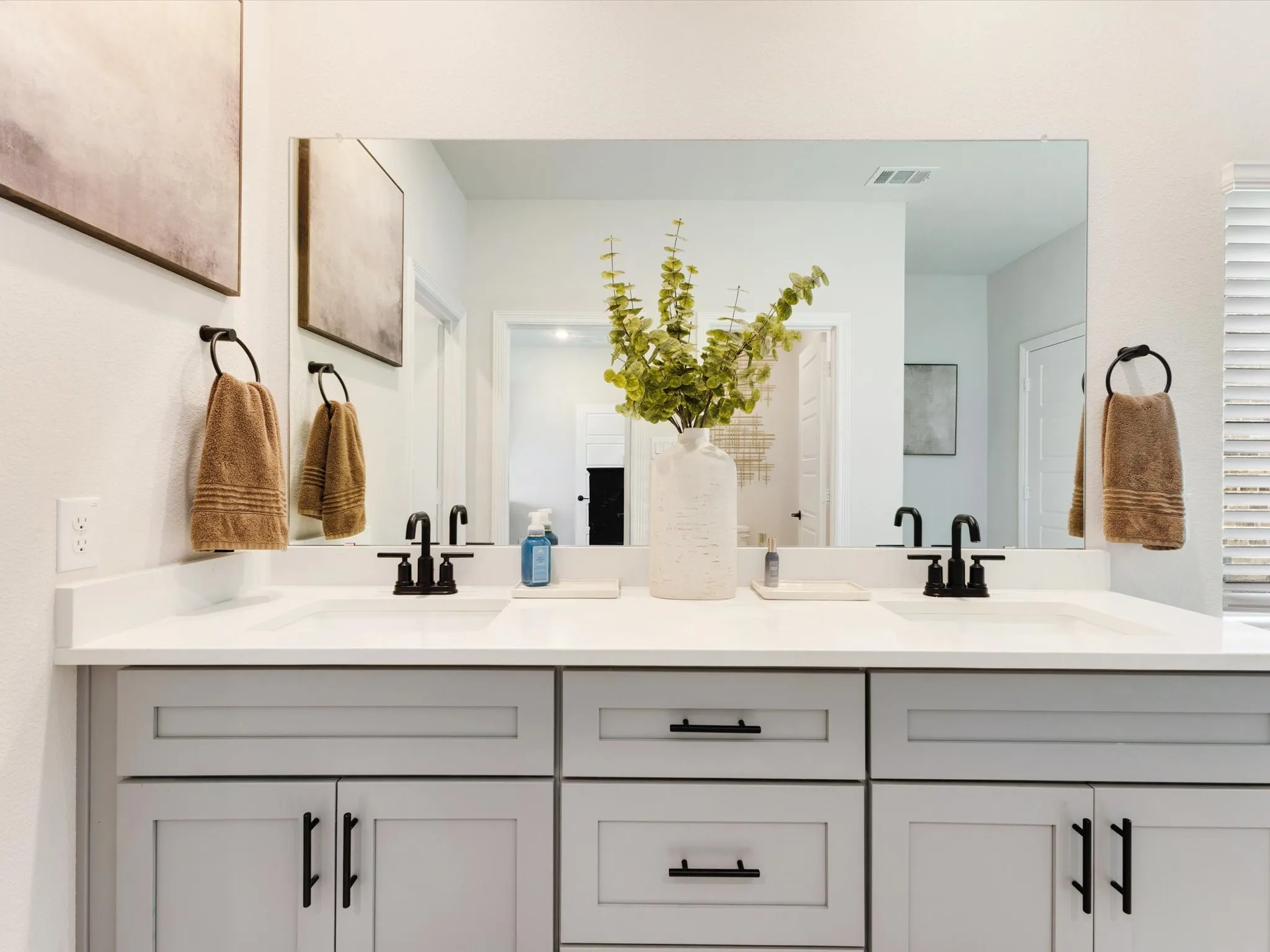 Double vanity featuring gray shaker-style cabinetry with matte black hardware, white countertops, and dual undermount sinks with matte black faucets
