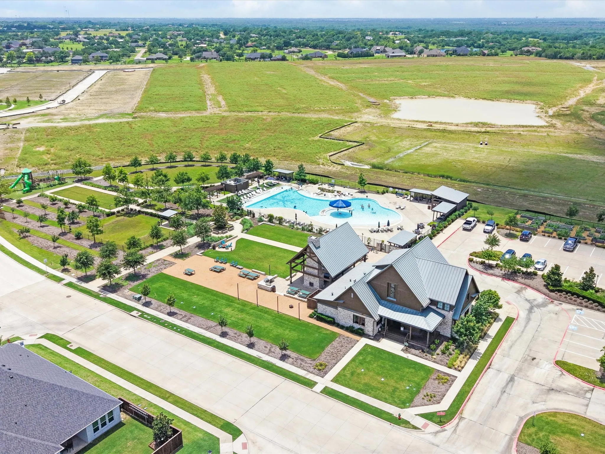 Community amenity center featuring a swimming pool, clubhouse, playground, and manicured green spaces