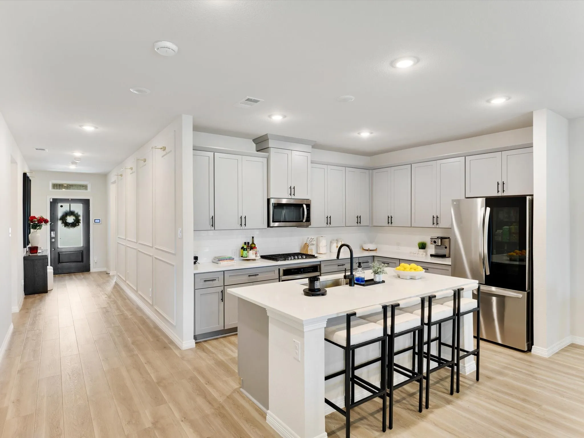 Open-concept kitchen featuring light-toned cabinetry, stainless steel appliances, a center island with countertop seating, and recessed lighting