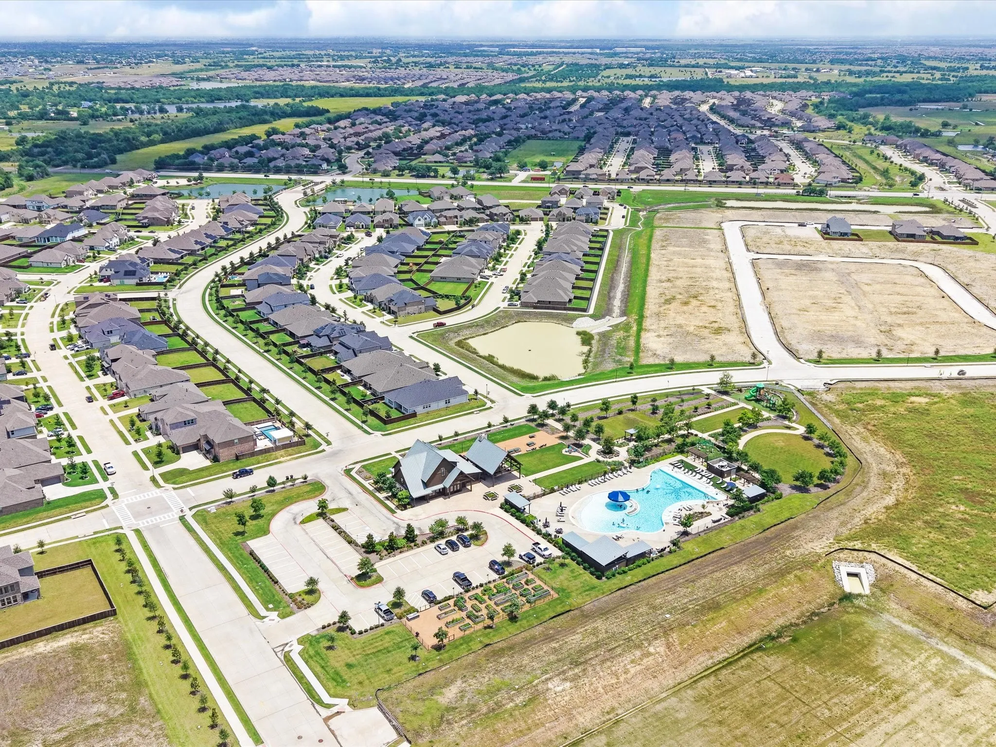 Aerial perspective showcasing a developed residential community with an amenity center featuring a swimming pool, clubhouse, and green spaces