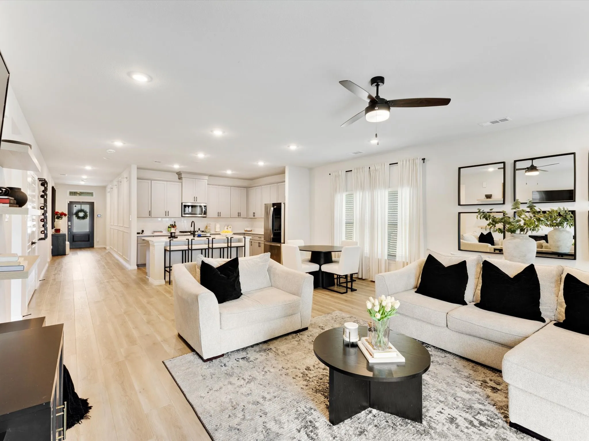 Open-concept living area featuring light wood-finish flooring, recessed lighting, a contemporary ceiling fan, and a kitchen with stainless steel appliances