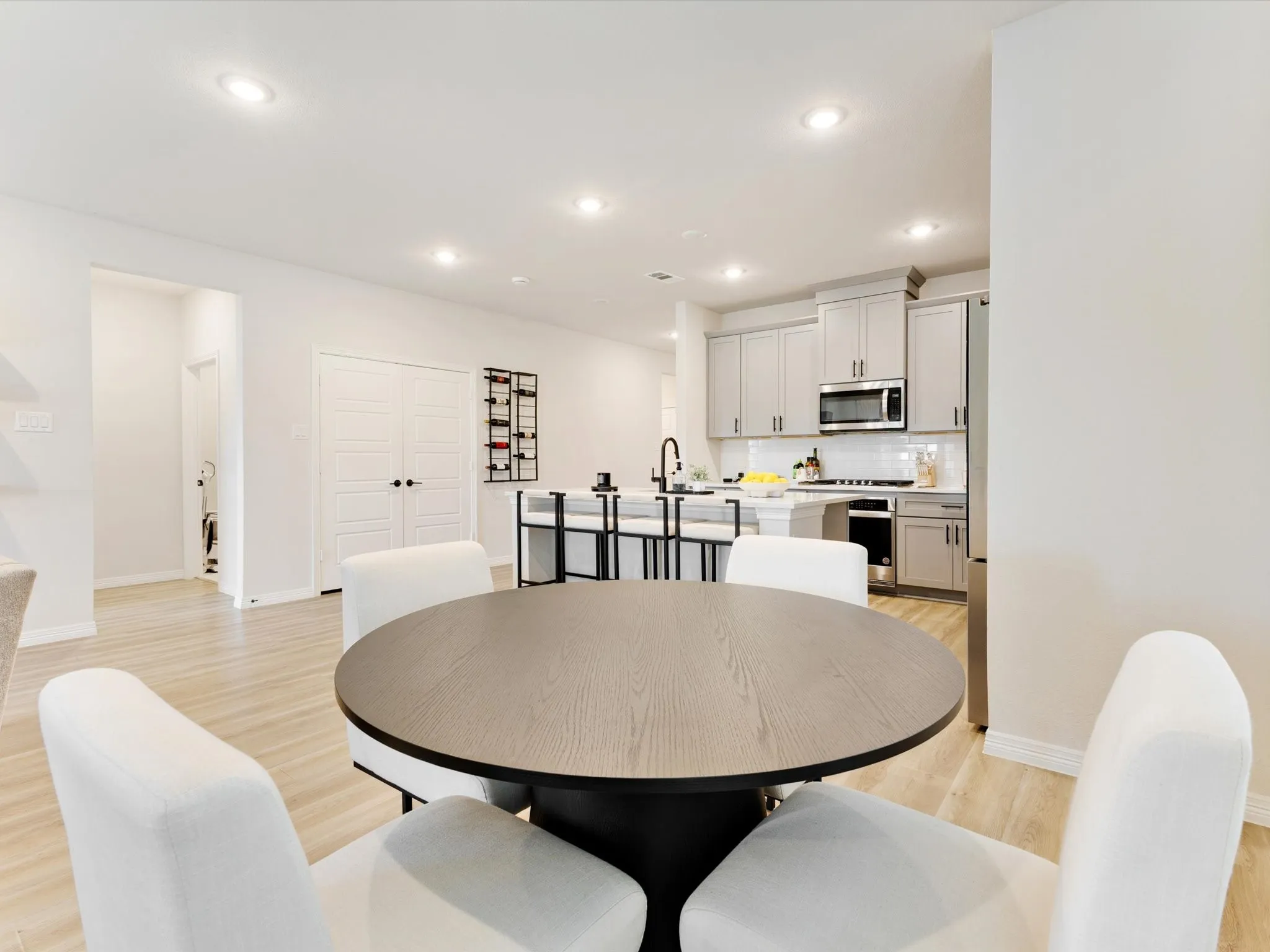 Open-concept living space with light wood-finish flooring, recessed lighting, white walls, and white baseboards