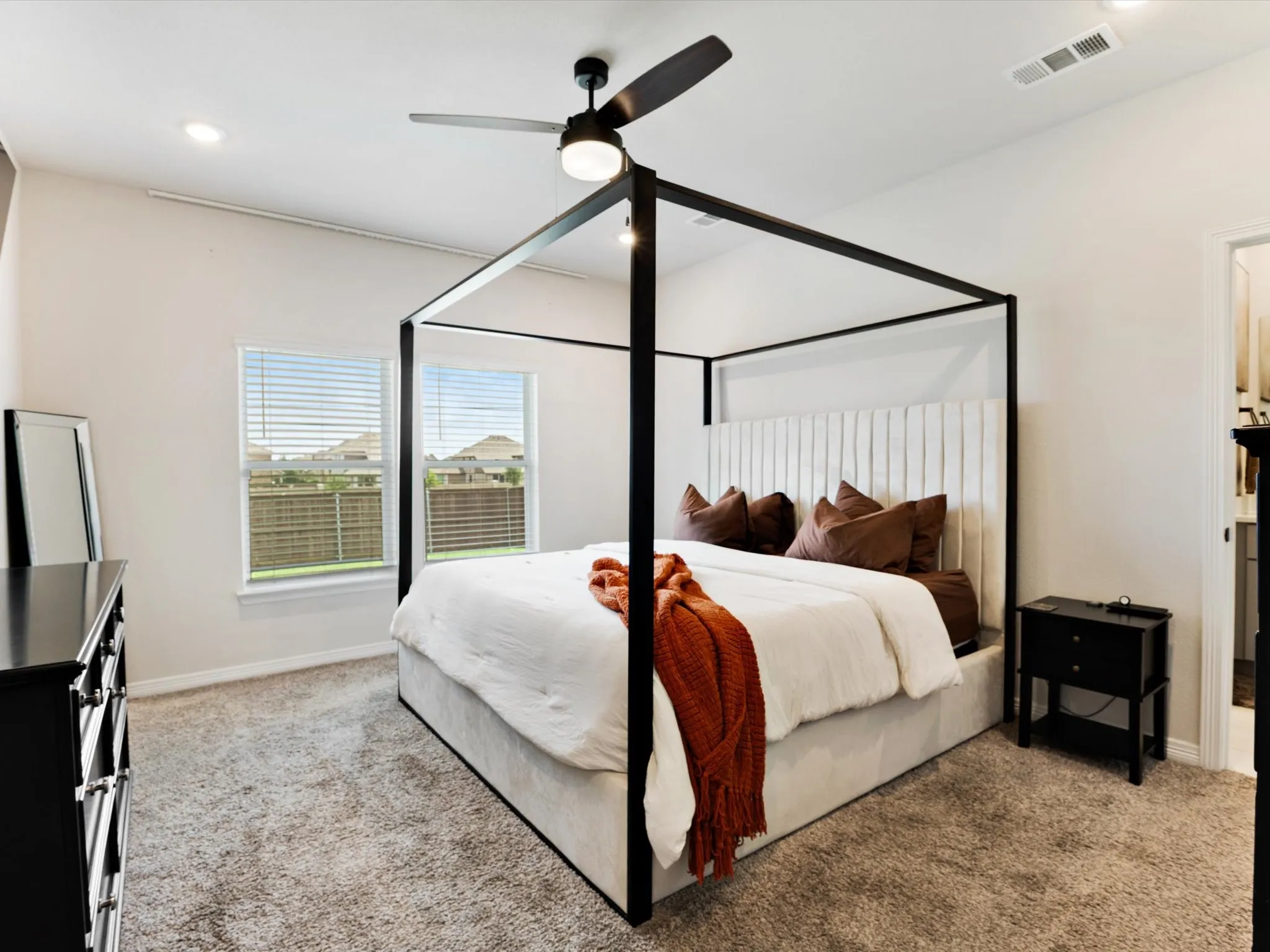 Carpeted bedroom with a dark-bladed ceiling fan featuring an integrated light fixture