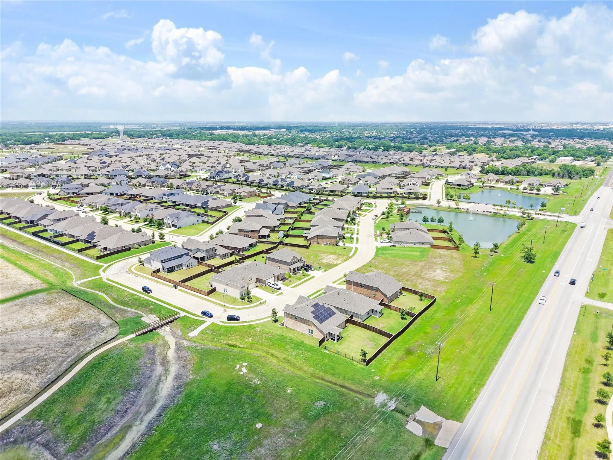 Aerial perspective of a developed residential area featuring multiple single-story homes with dark roofs