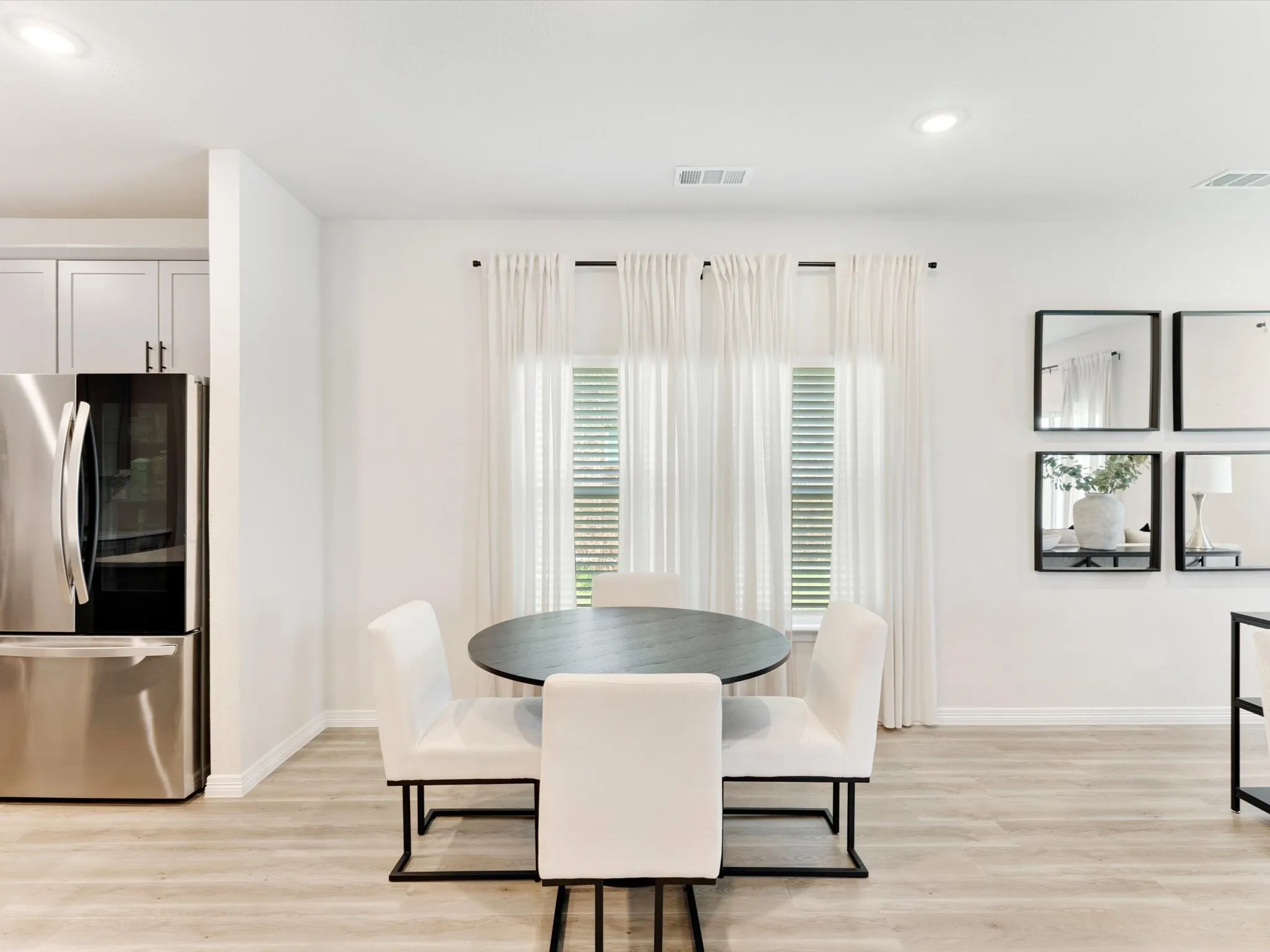 Dining area with wood-finish flooring, recessed lighting, and a window with blinds and sheer curtains