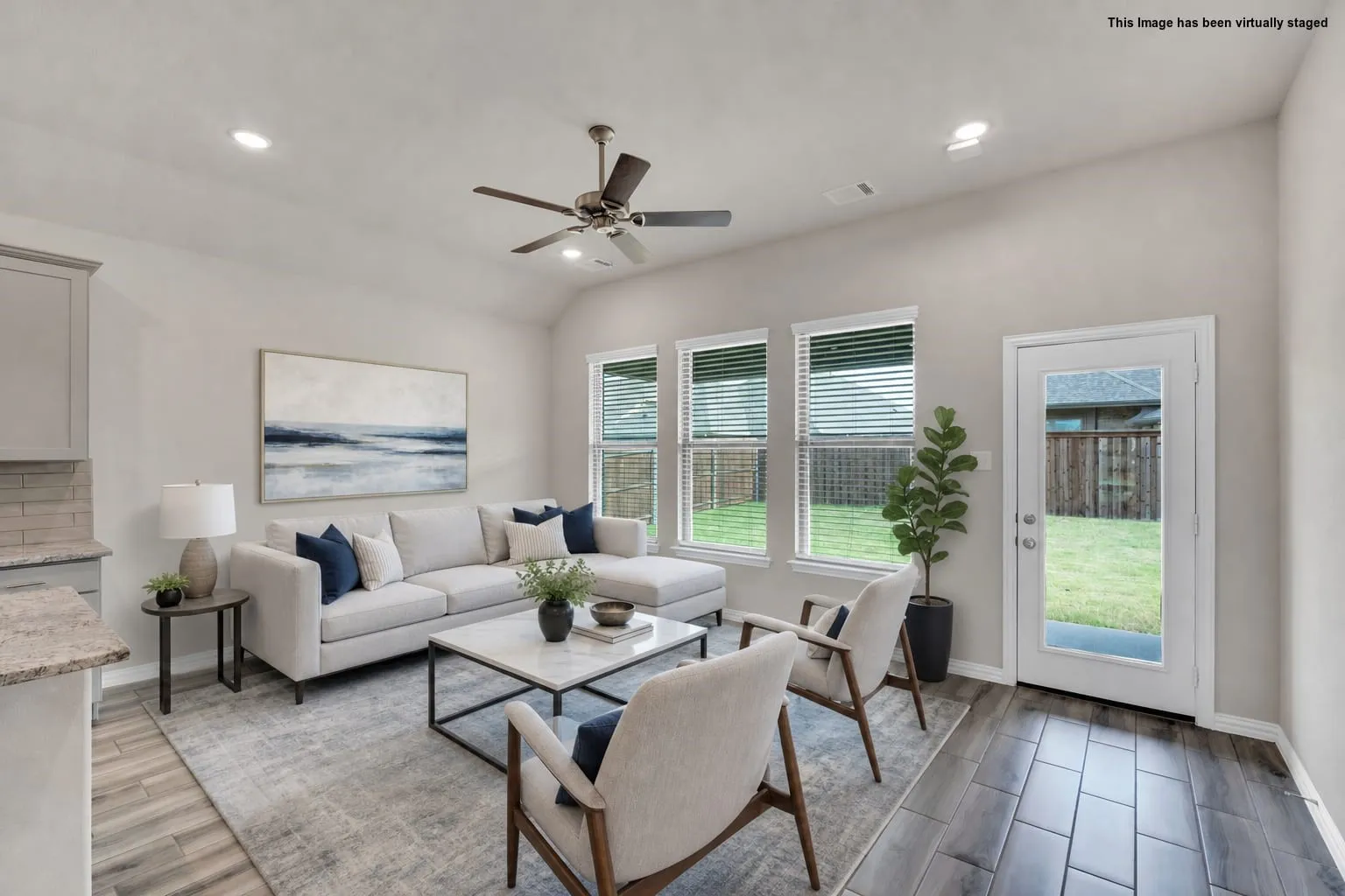 Spacious living area featuring wood-look tile flooring, recessed lighting, and a ceiling fan. Virtual Staging