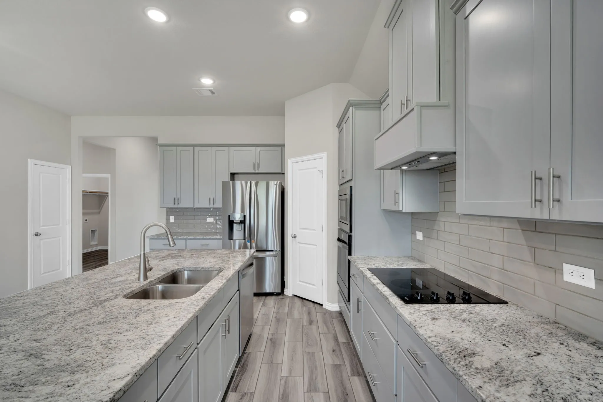 Kitchen area with wood-finish flooring, light gray cabinetry, stainless steel