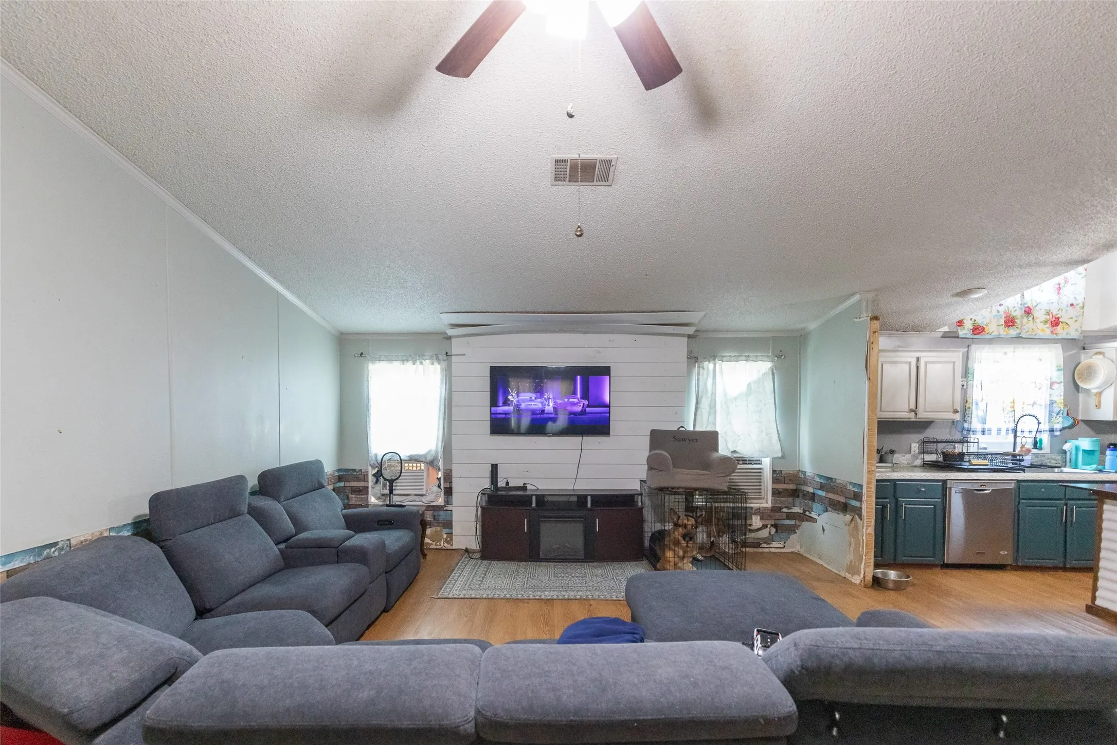 Living area with wood-finish flooring, ceiling fan, and shiplap accent wall