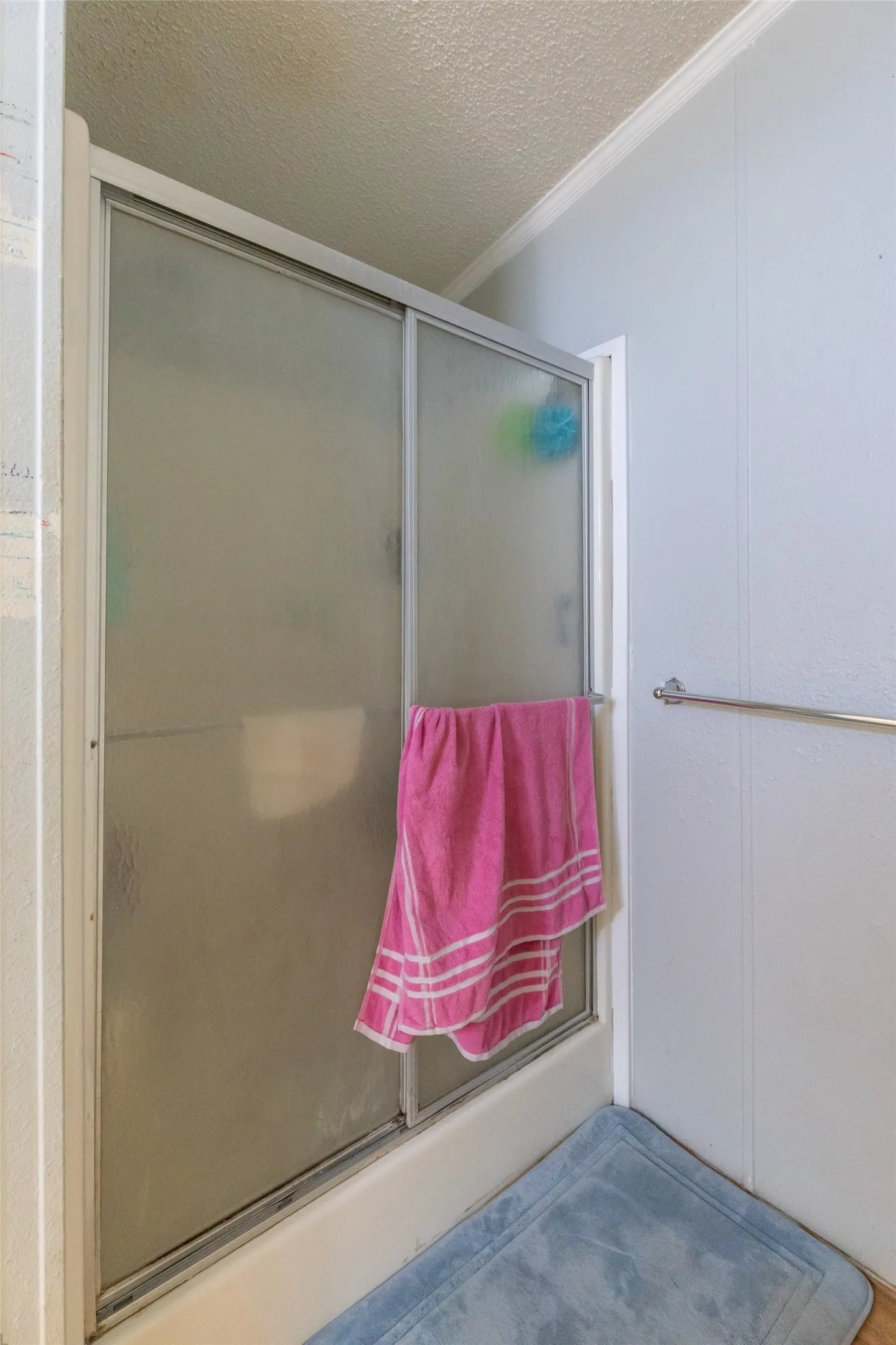 Shower enclosure with frosted glass panels, white frame, and chrome towel bar