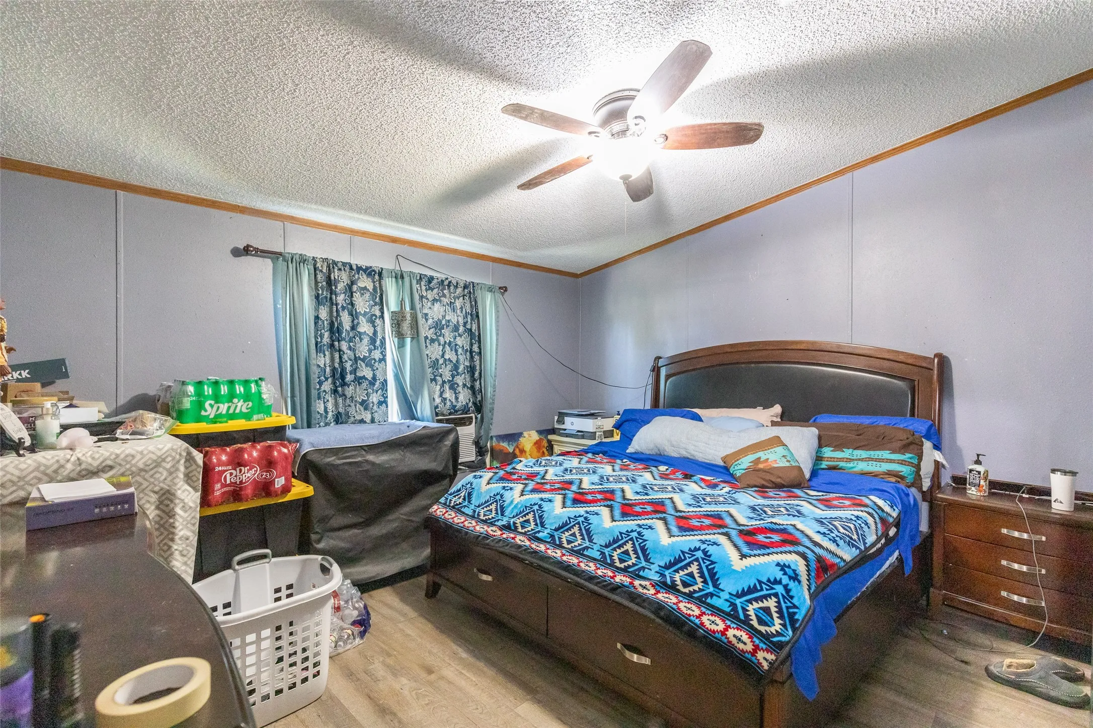 Room featuring wood-finish flooring, a ceiling fan with integrated lighting, and light blue wall paneling