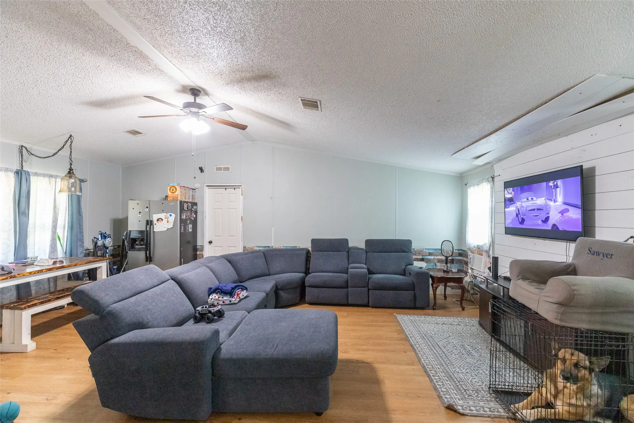 Spacious living area featuring wood-finish flooring, a ceiling fan, and light-toned walls
