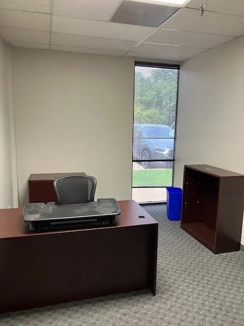 Windowed interior room with neutral wall tones and patterned carpet flooring