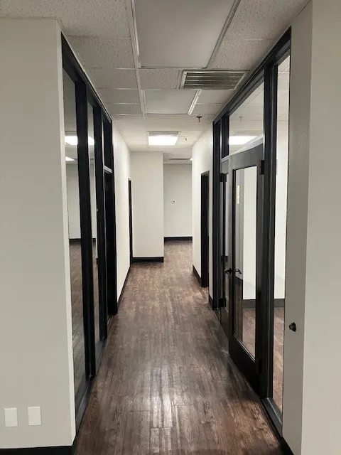 Hallway with wood-finish flooring, white walls, and black trim