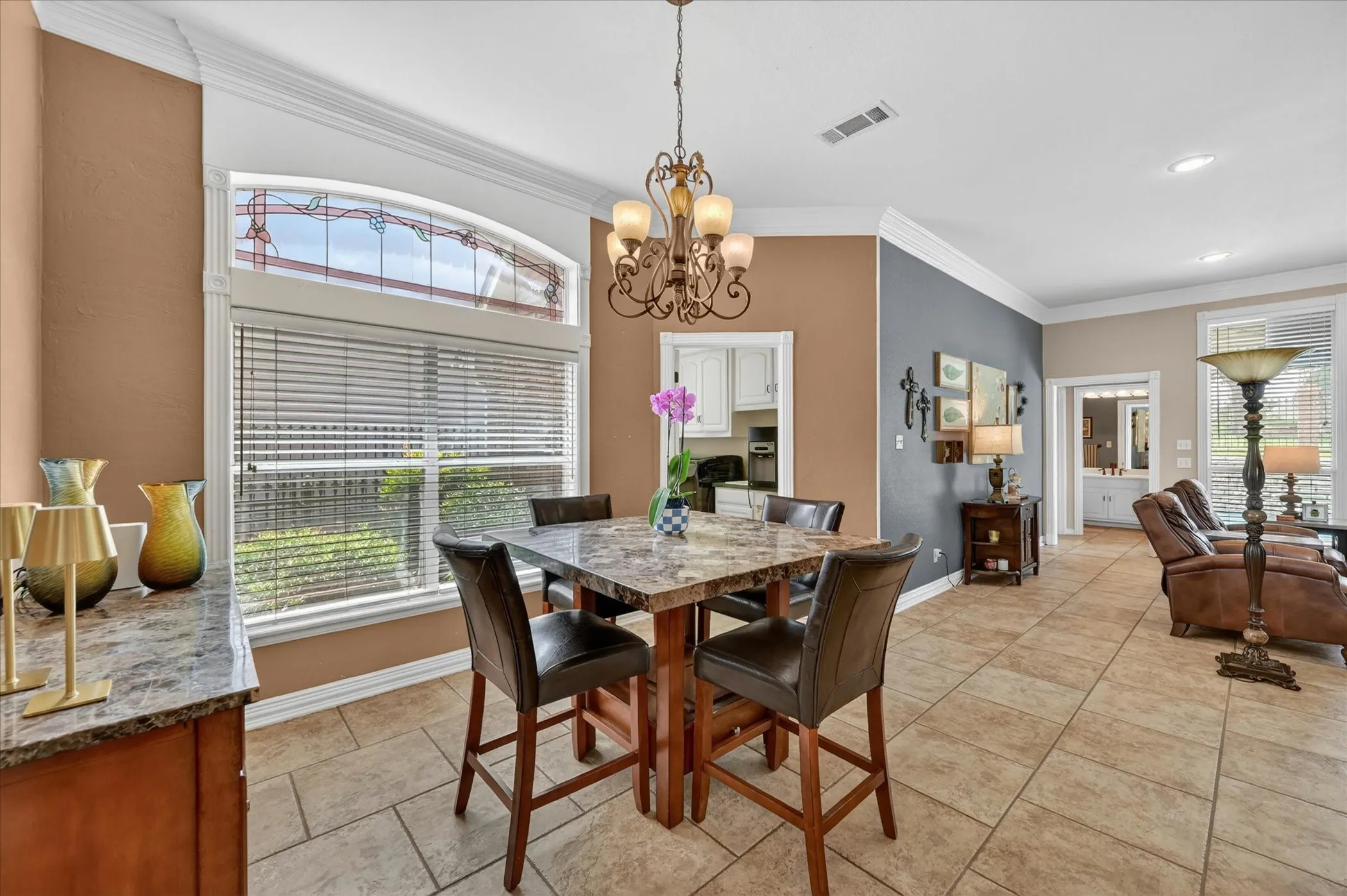 Dining area featuring a decorative chandelier, large window with stained glass transom, and tile flooring