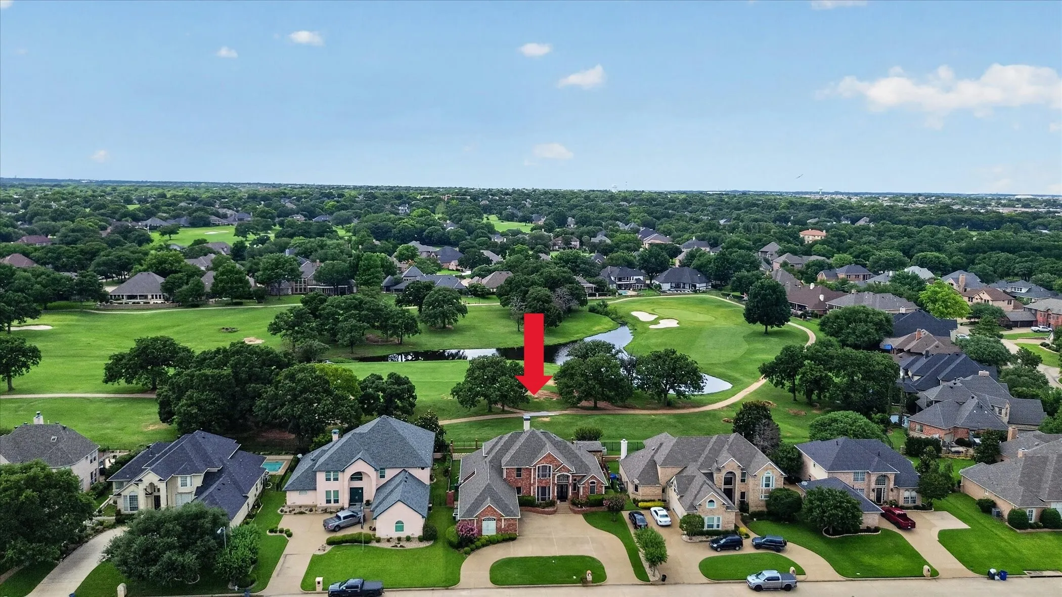 Aerial view showcasing a brick-clad residence with a multi-gabled roof and a paved driveway