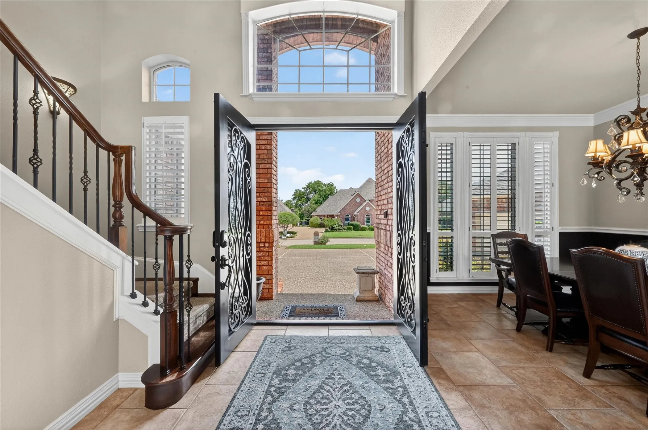 Grand entryway with decorative wrought iron double doors and a transom window