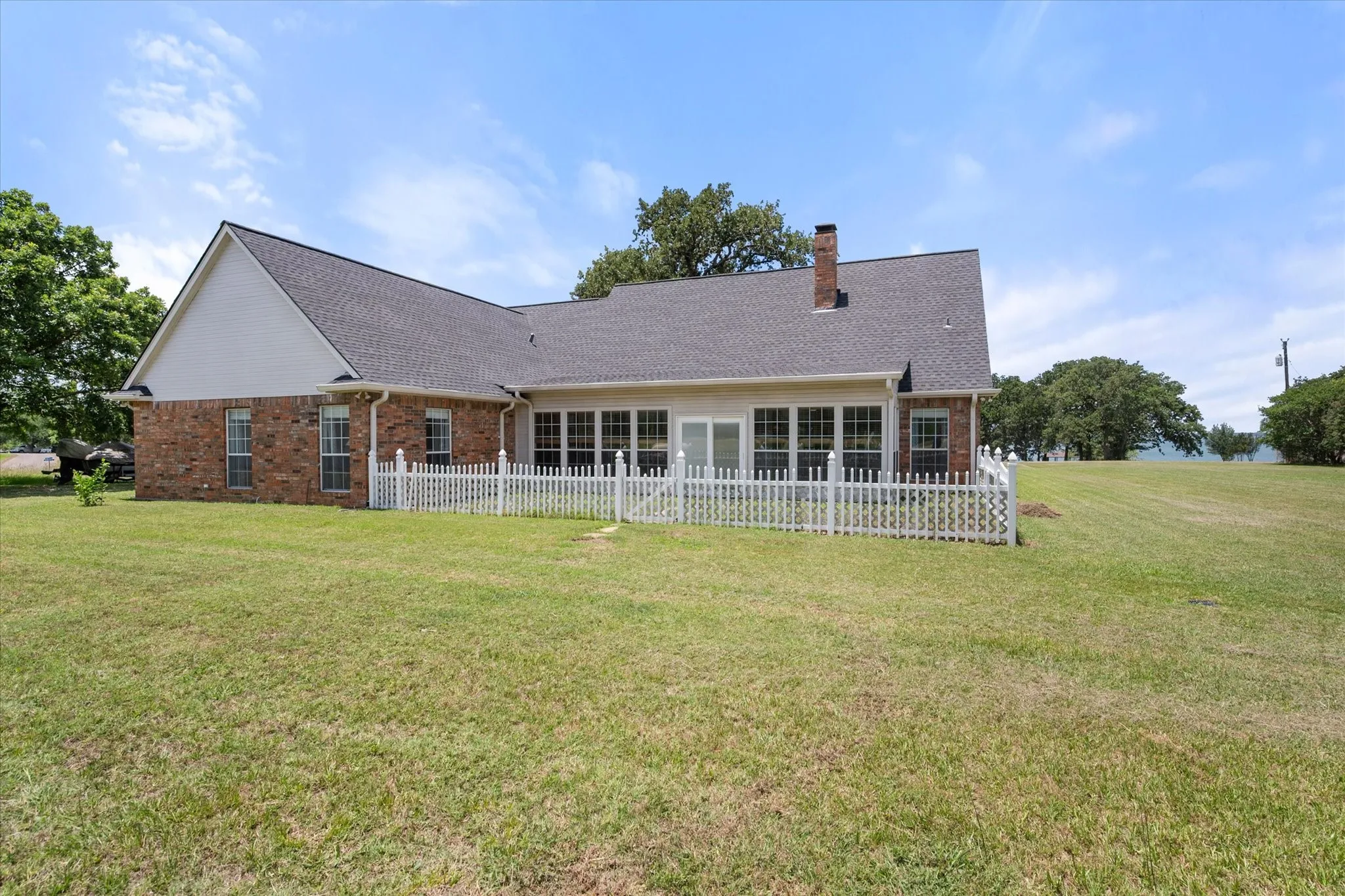 Rear exterior in Streetman, TX featuring brick construction, fenced patio area, and a spacious 1-acre yard.