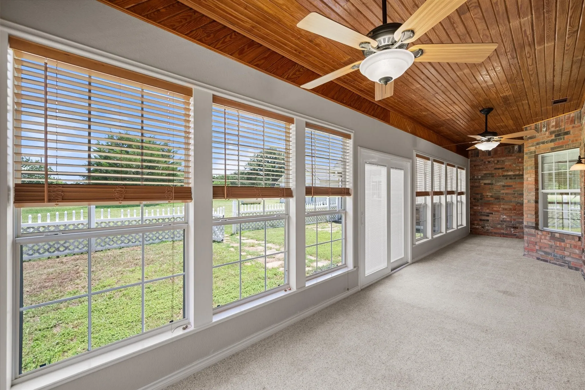 Enclosed sunroom in Streetman, TX with wood ceiling, large windows, and views of the fenced patio and yard.