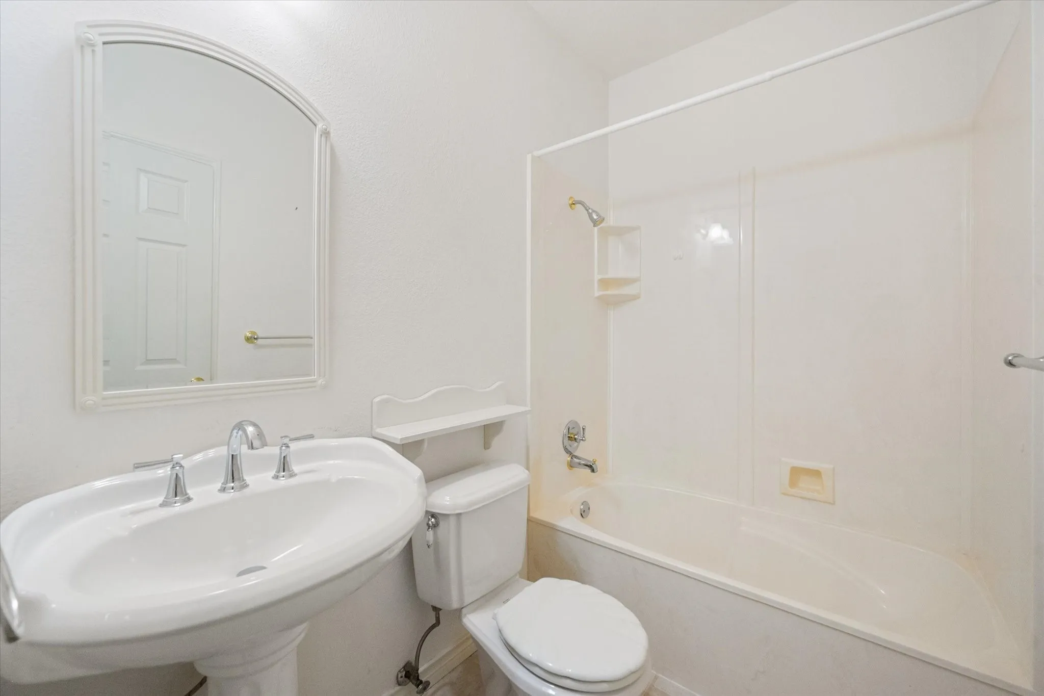 Full bathroom near Corsicana with tub-shower combo, pedestal sink, and neutral finishes.