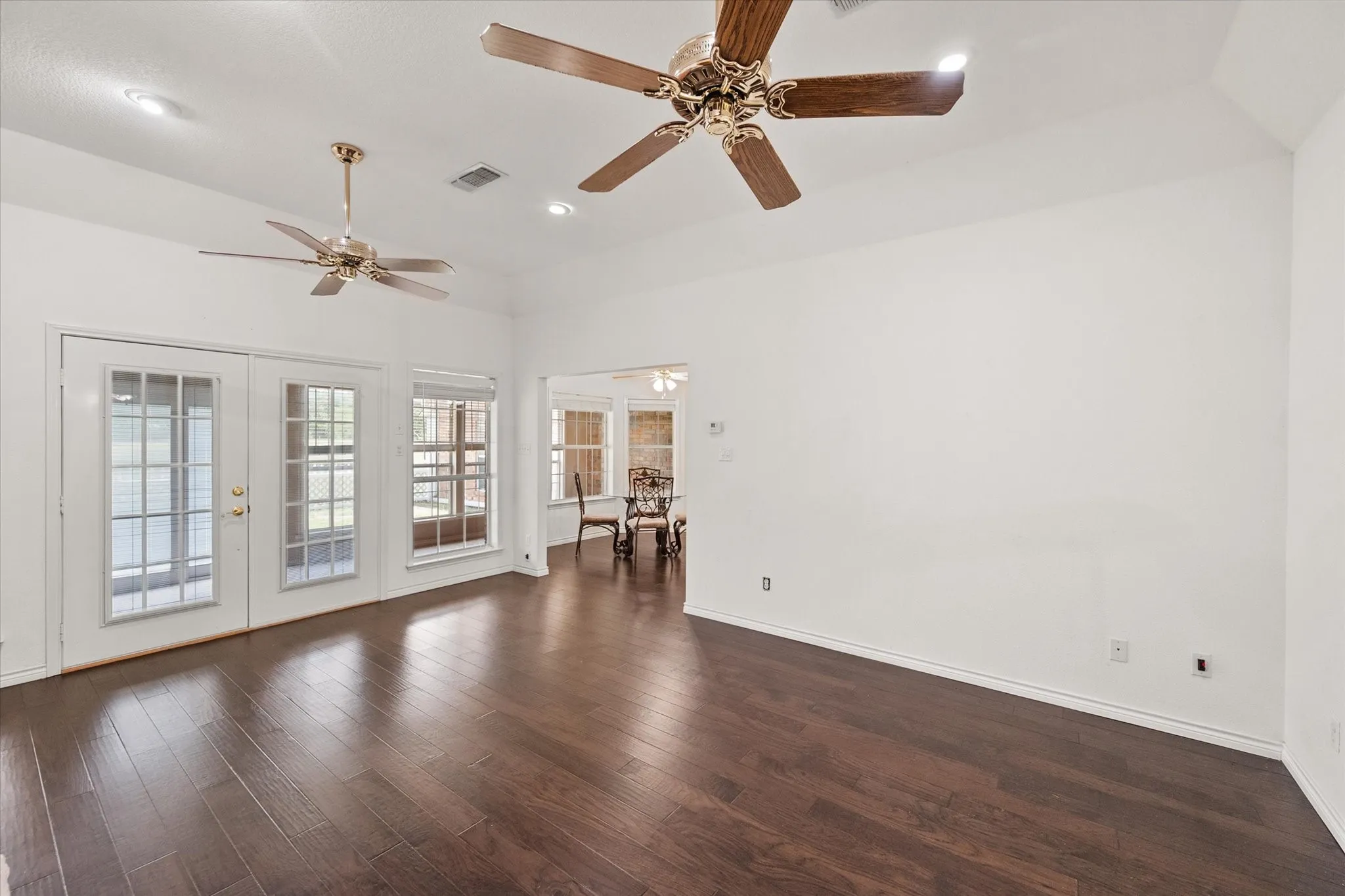 Open living room near Dallas with wood floors, tall ceilings, and flexible space for relaxing or entertaining.