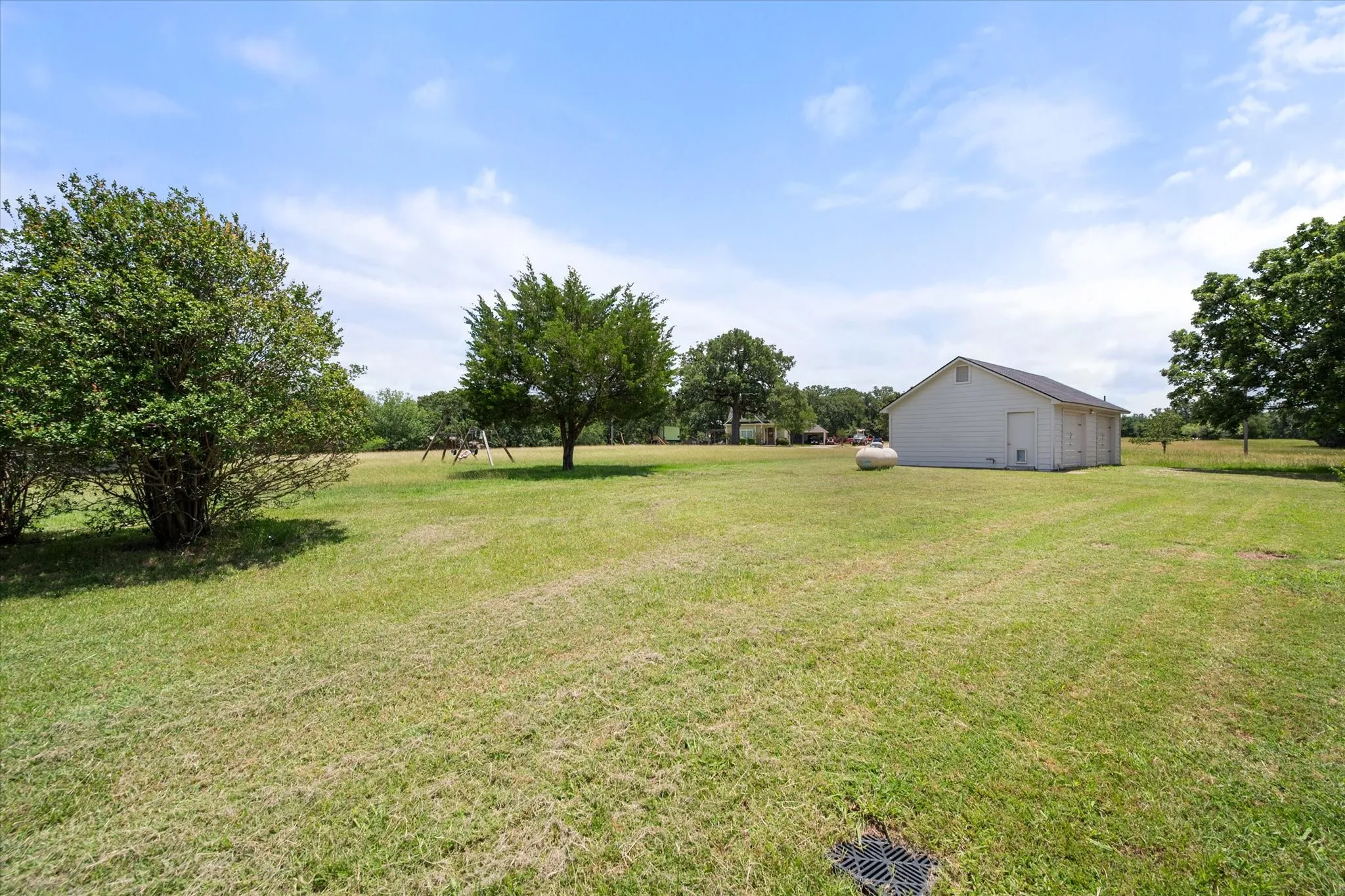 Large yard near Richland Chambers Lake with mature trees, open lawn, and detached garage or storage building.