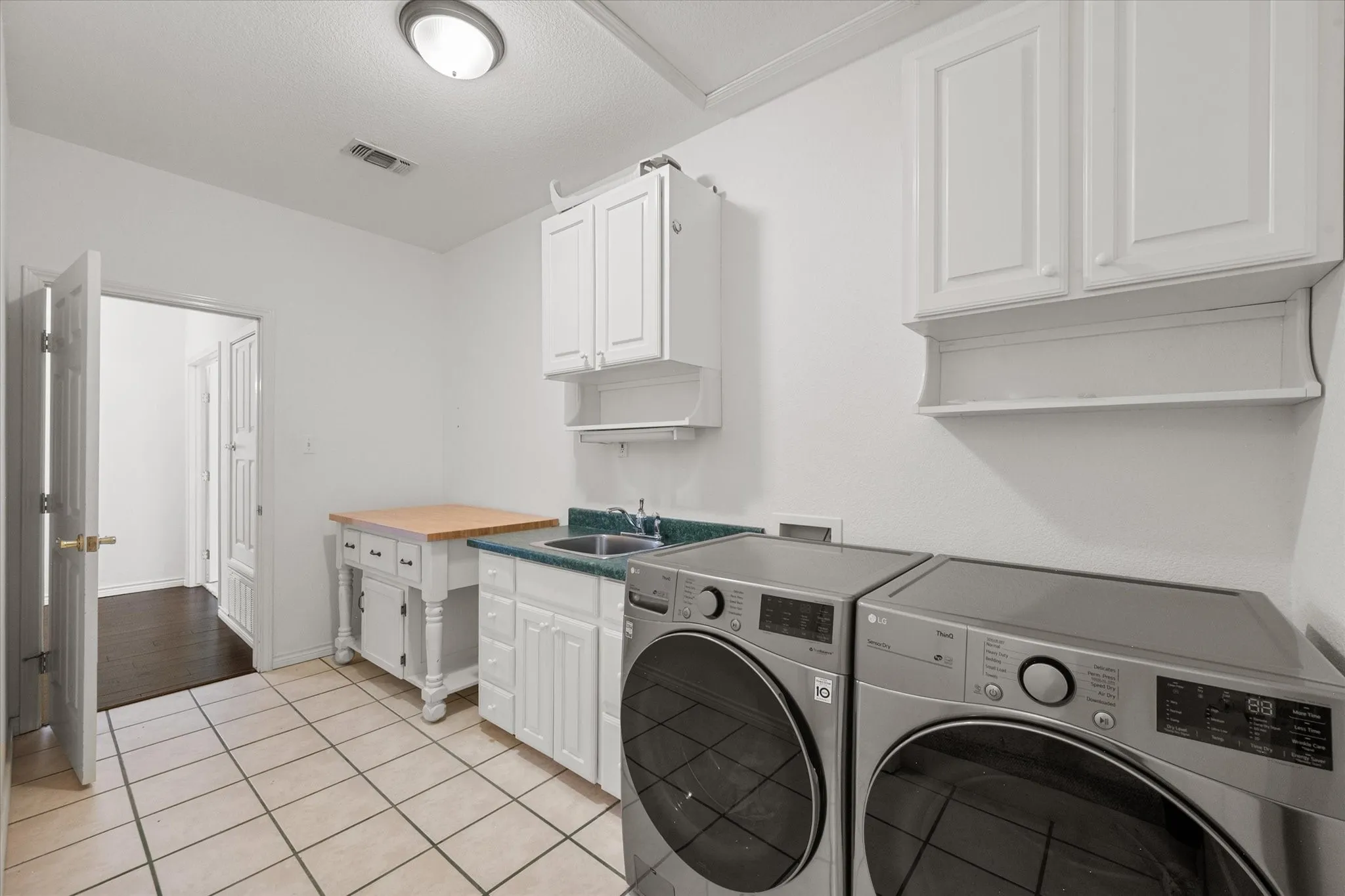 Spacious laundry room near Richland Chambers Lake featuring cabinets, sink, tile flooring, and room for full-size appliances.